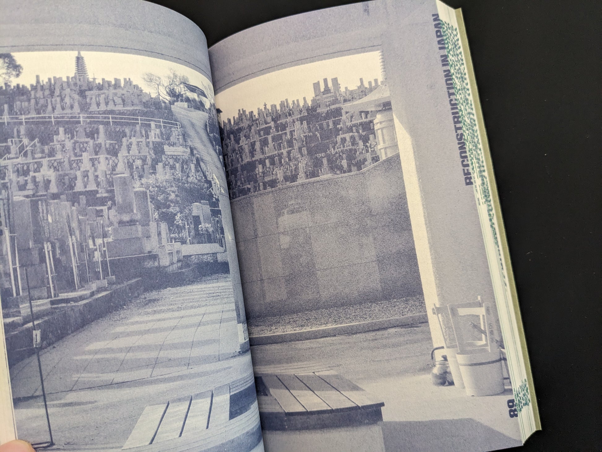 Bilingual spread discussing Japanese cemetery reconstruction in monochrome blue.