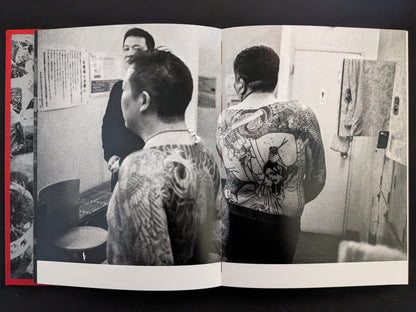 Rear view of tattooed men in a tiled Japanese bathroom.
