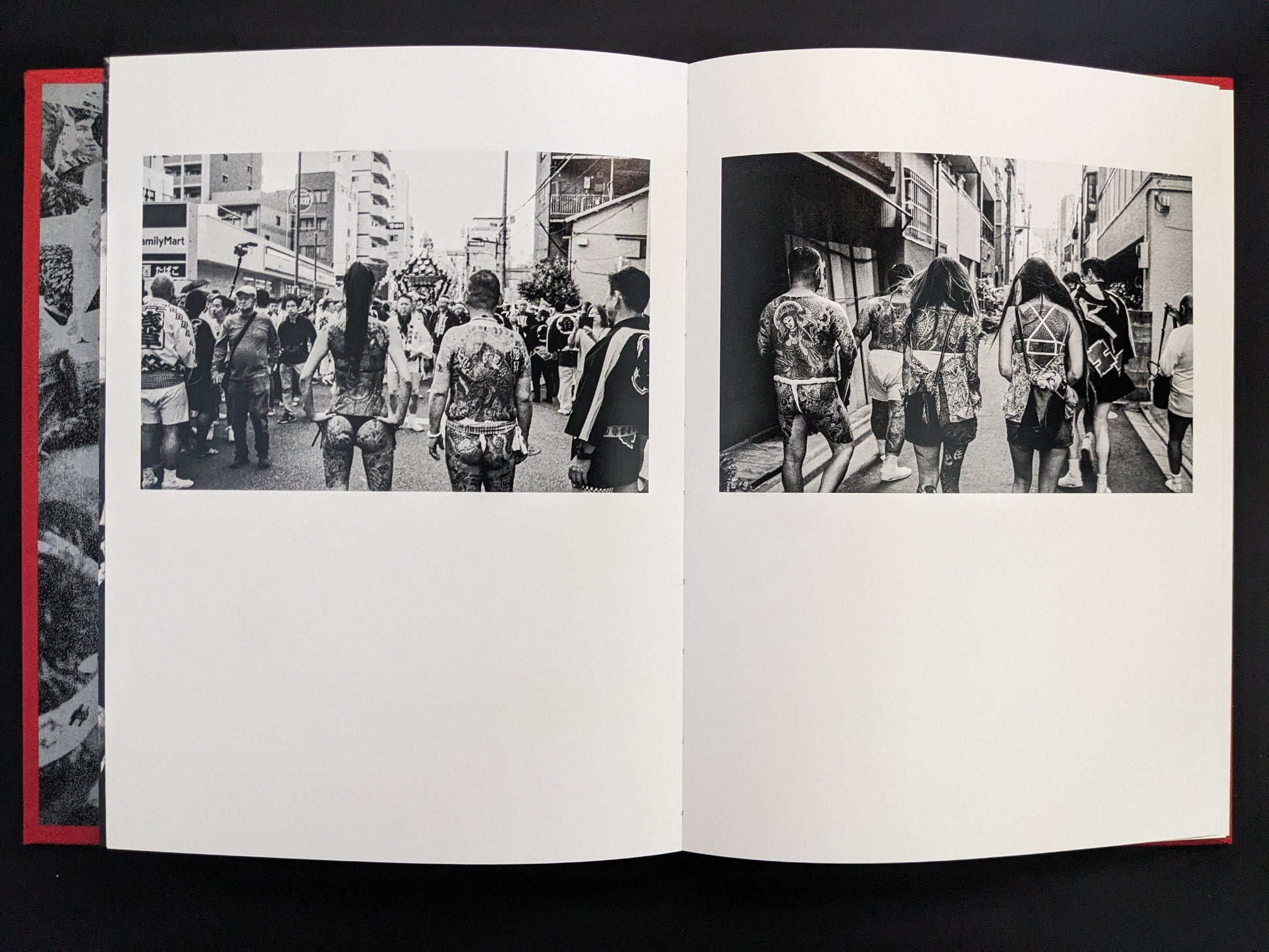Black-and-white photo of tattooed men walking during a festival