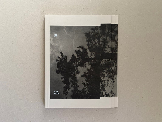 Front cover of Ash (New Edition) by Muge, showing a dark tree silhouette against a grey sky on a folded softcover.