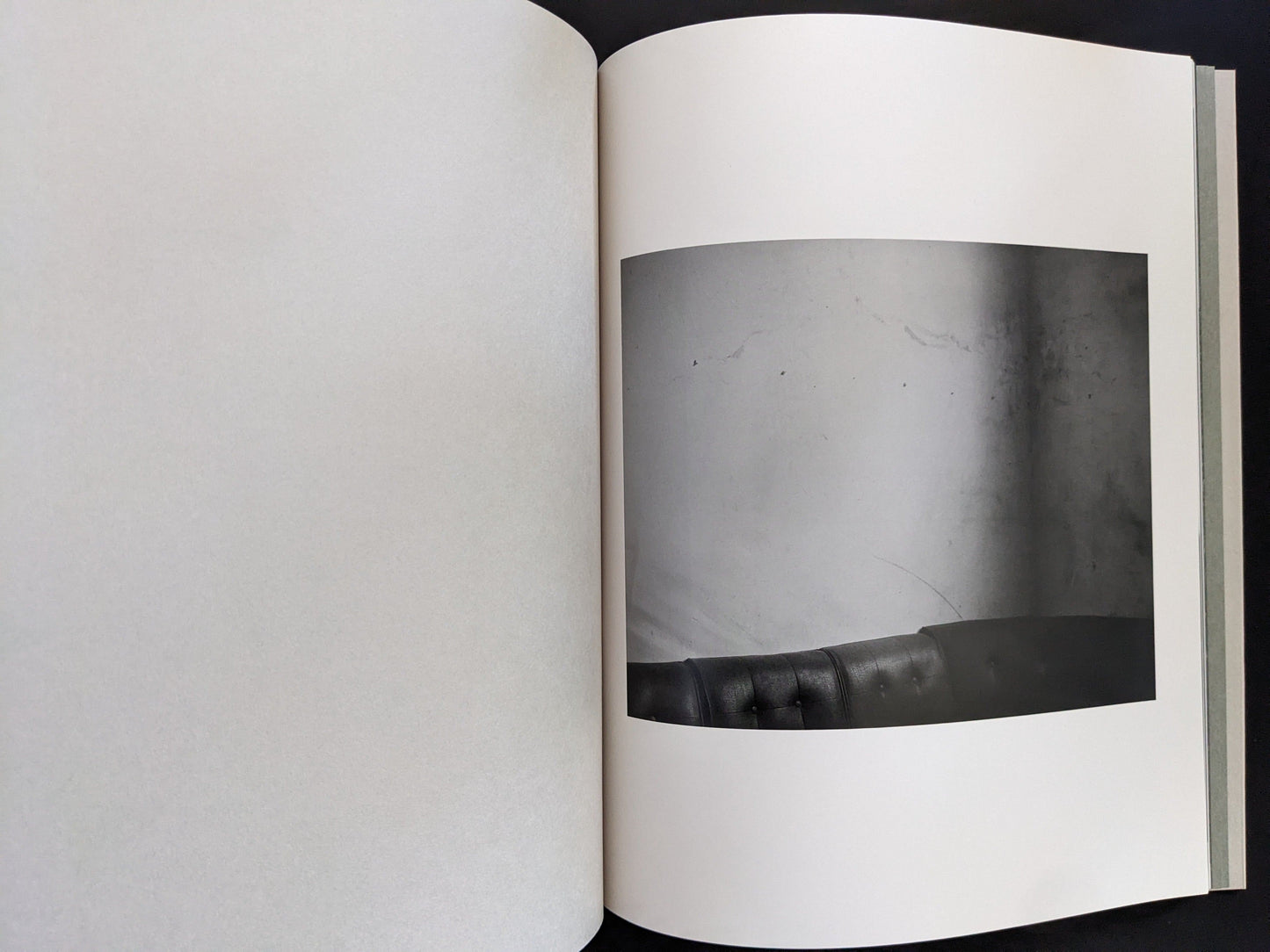 Open spread from ASH (New Edition) by Muge, showing a minimalist black-and-white still life with a sofa backrest.