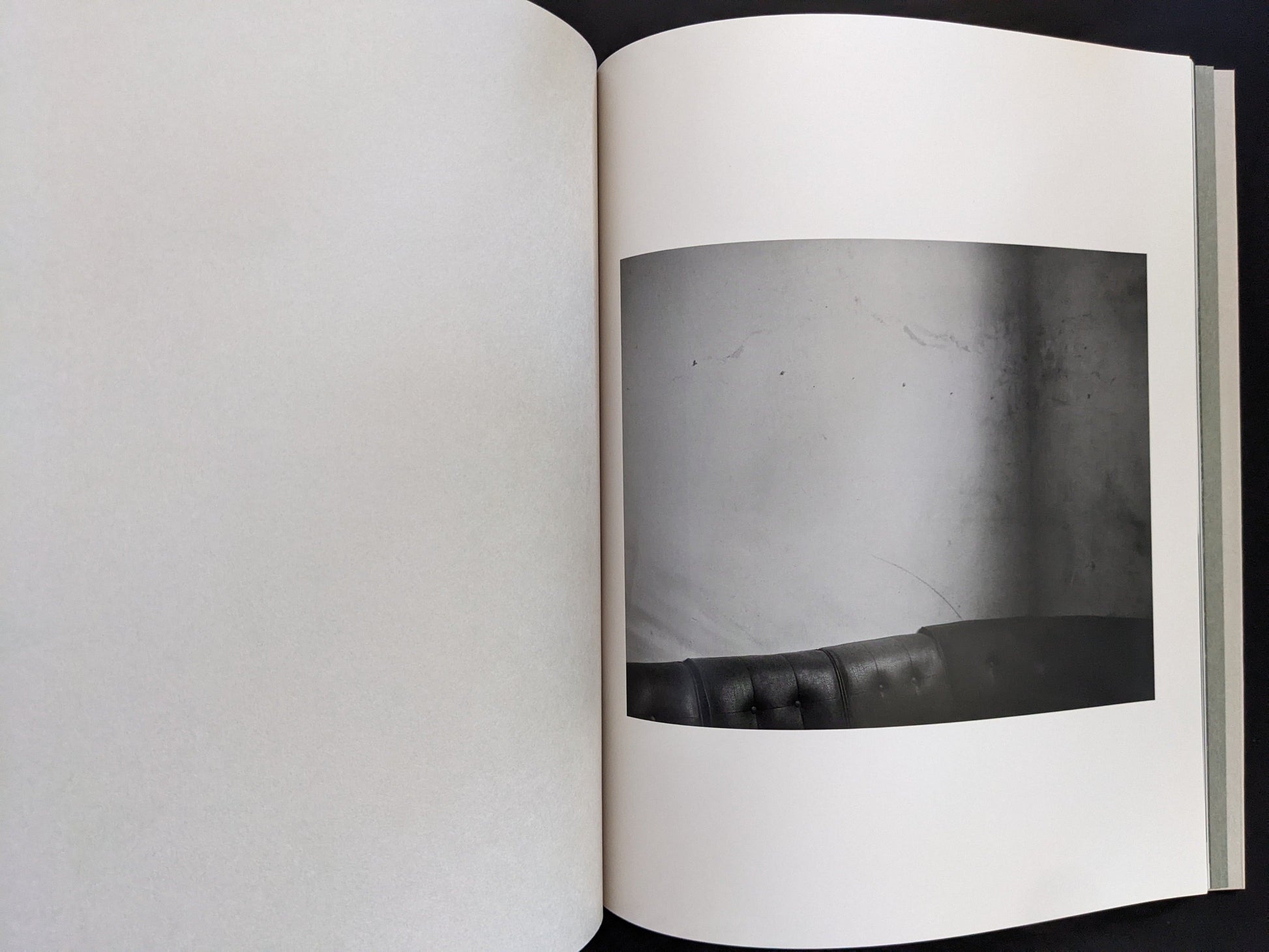 Open spread from ASH (New Edition) by Muge, showing a minimalist black-and-white still life with a sofa backrest.