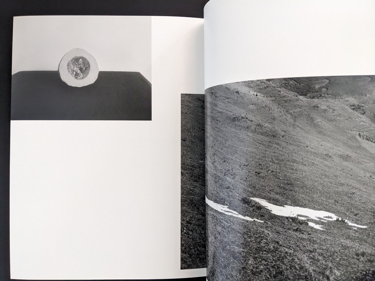 Open spread from ASH (New Edition) by Muge, showing a close-up black-and-white photograph of textured rock surfaces.