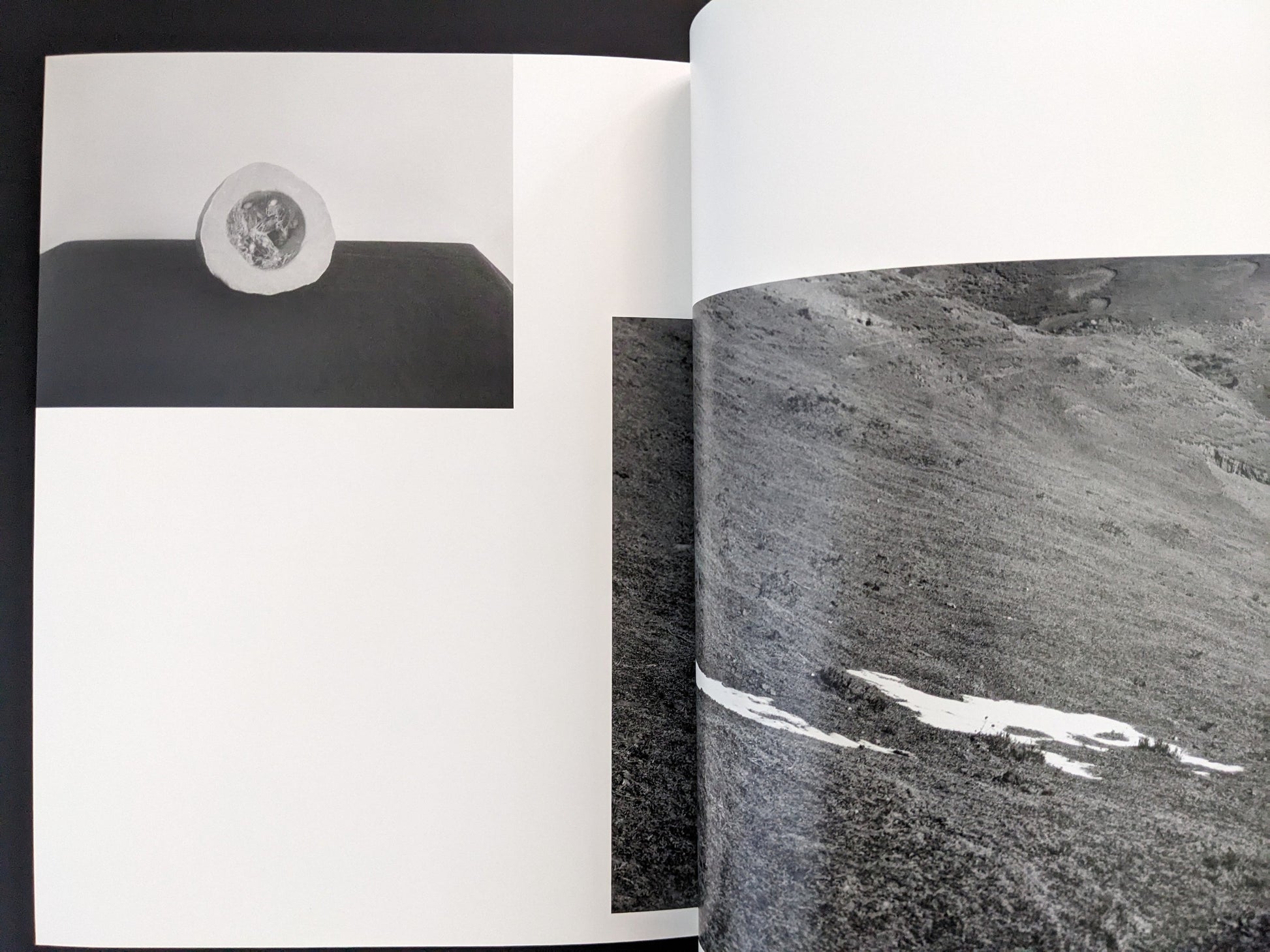 Open spread from ASH (New Edition) by Muge, showing a close-up black-and-white photograph of textured rock surfaces.