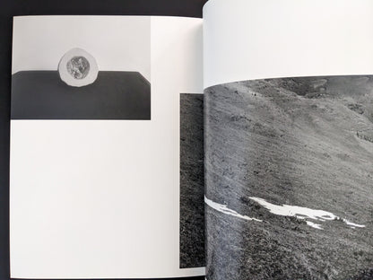 Open spread from ASH (New Edition) by Muge, showing a close-up black-and-white photograph of textured rock surfaces.