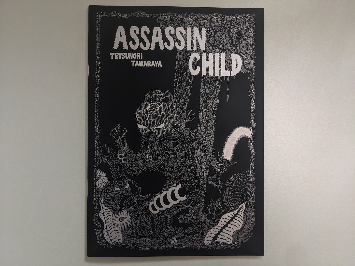 Front cover of Assassin Child by Tetsunori Tawaraya – detailed silver ink illustration of mutant creatures in a forest setting