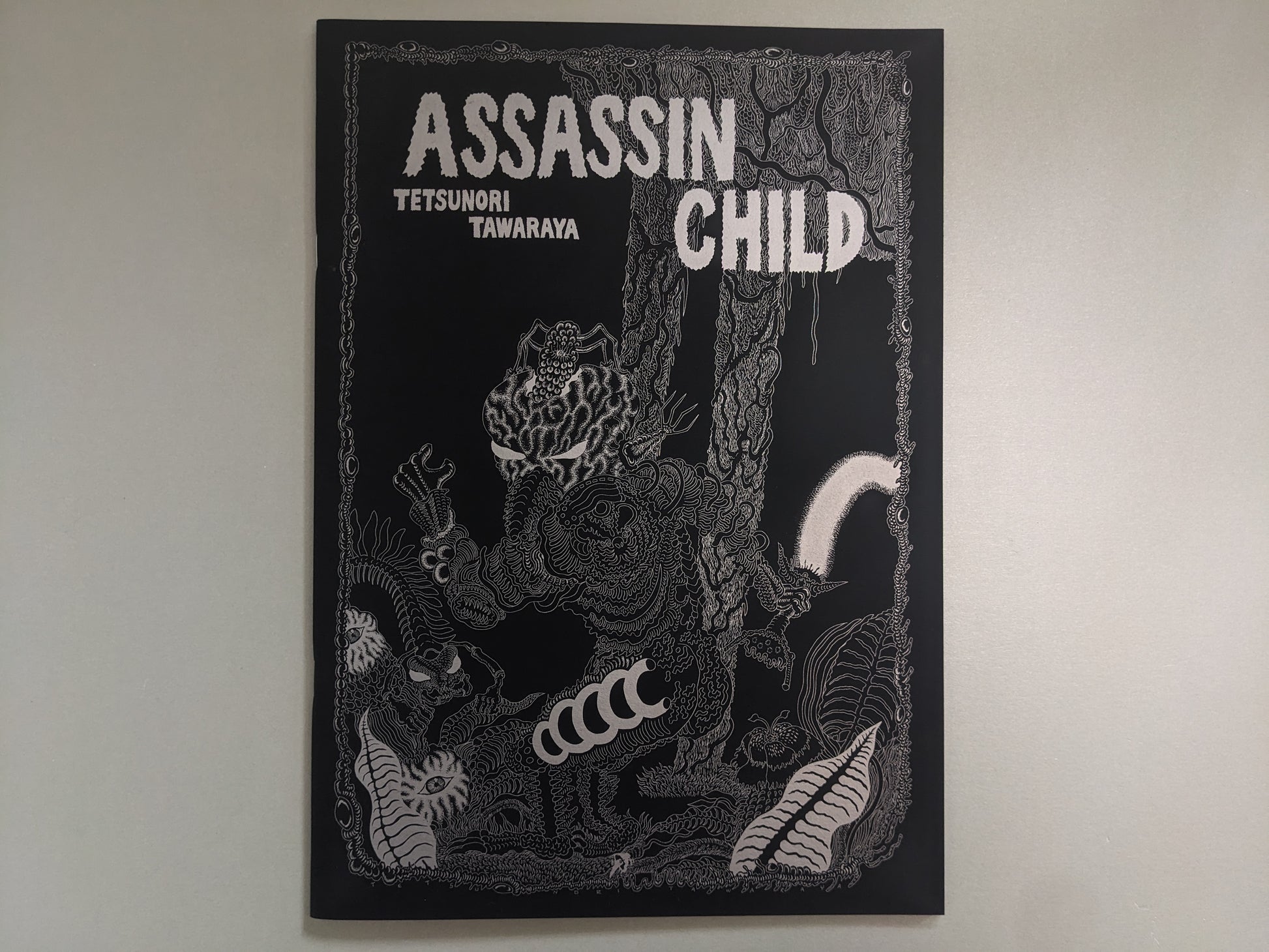 Front cover of Assassin Child by Tetsunori Tawaraya – detailed silver ink illustration of mutant creatures in a forest setting