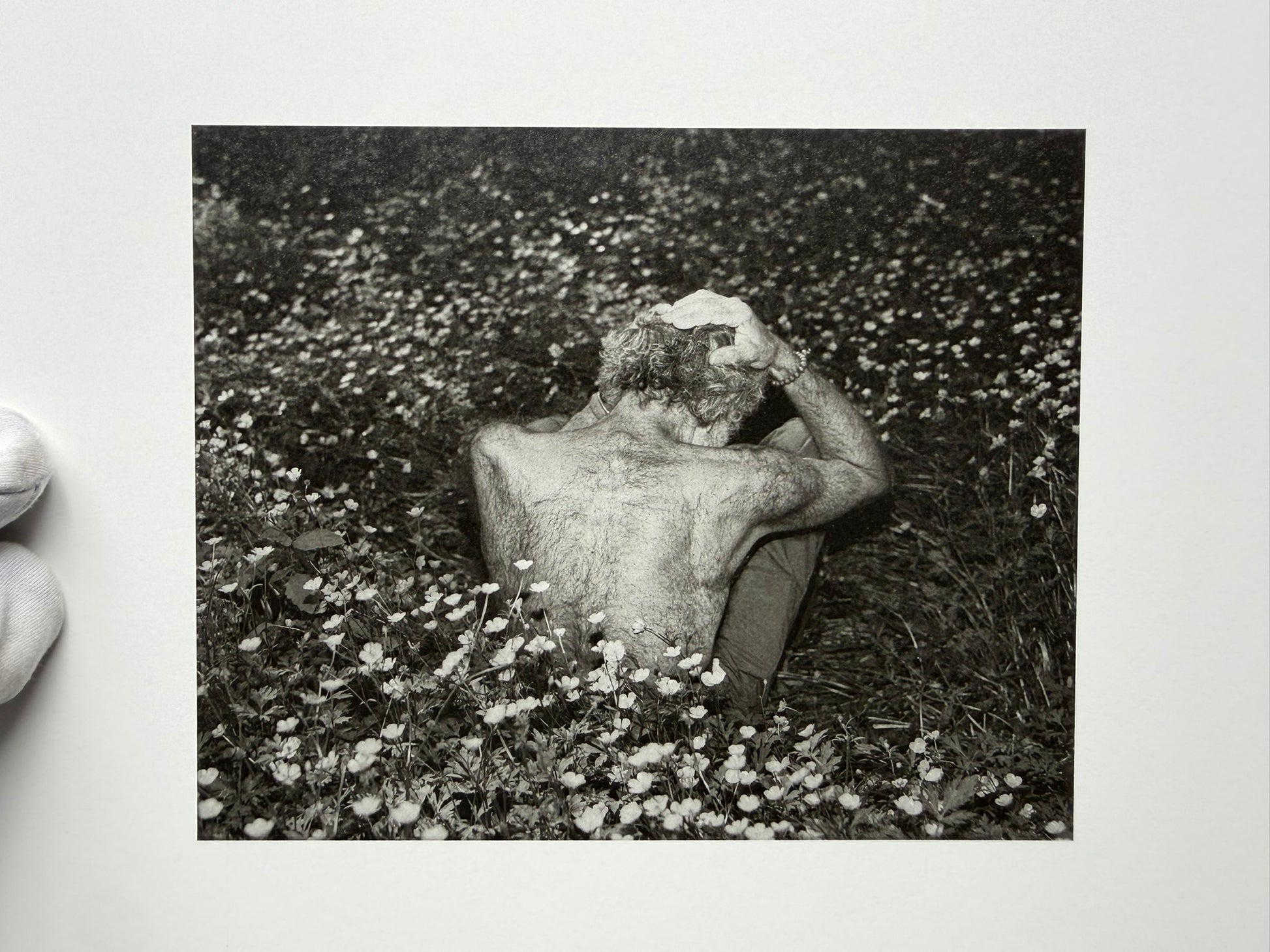 At Night Gardens Grow by Pia-Paulina Guilmoth, black-and-white portrait of a person lying in flowers and pointing upward
