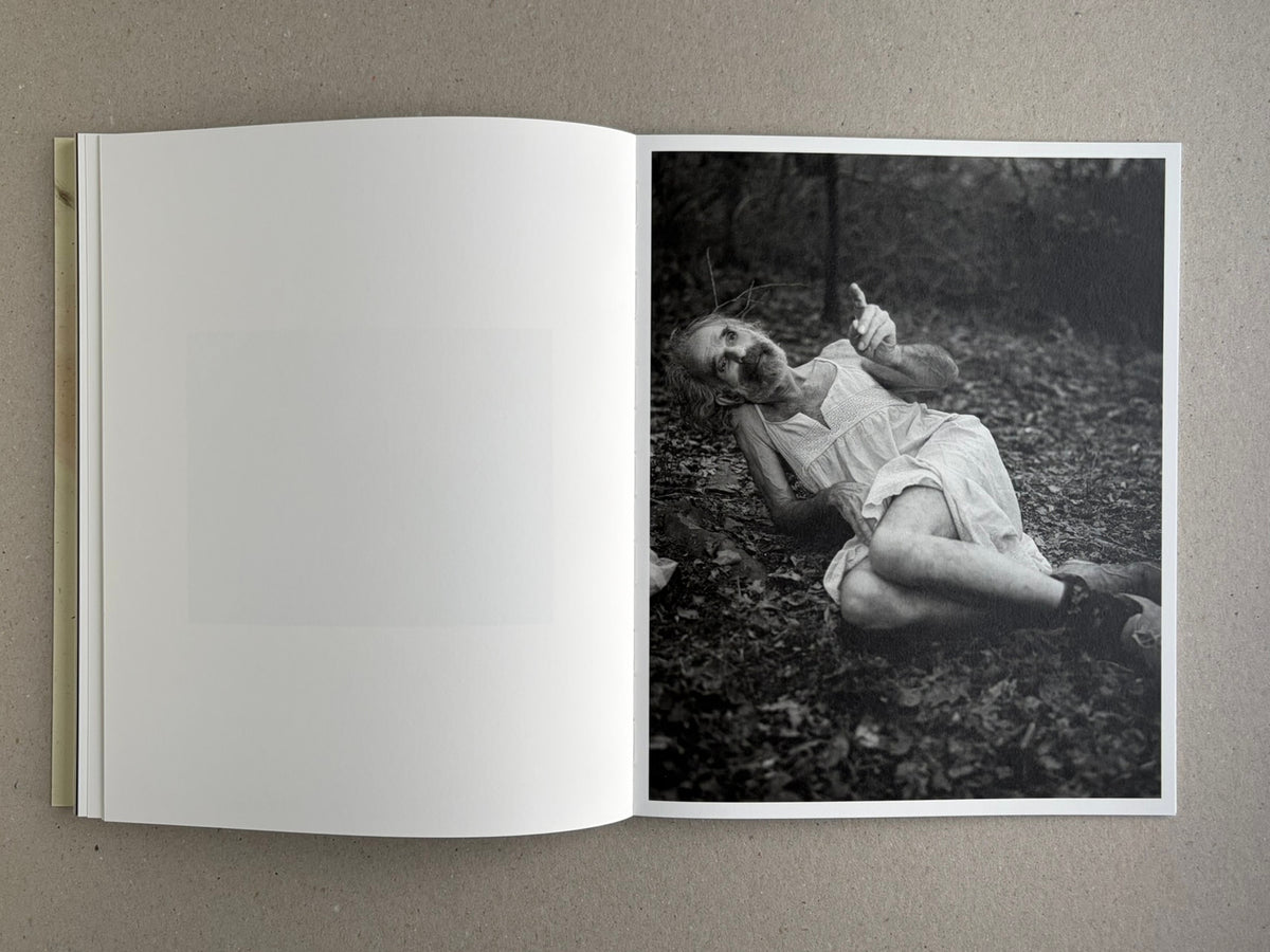 At Night Gardens Grow open to a black-and-white portrait of a person reclining on a forest floor
