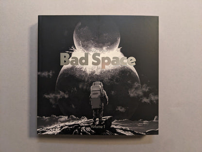 Front cover of Bad Space – Volume 1 by Scott Base with hot silver stamping; astronaut facing a split moon; softcover, 20×20 cm.