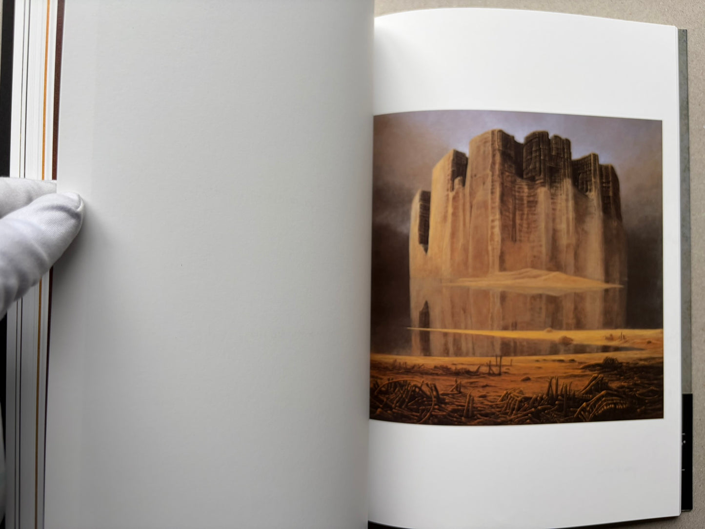 Open spread from Beksinski - The Collected Works I ver. 1.2 with a large ochre painting of a block-like structure in a barren landscape.
