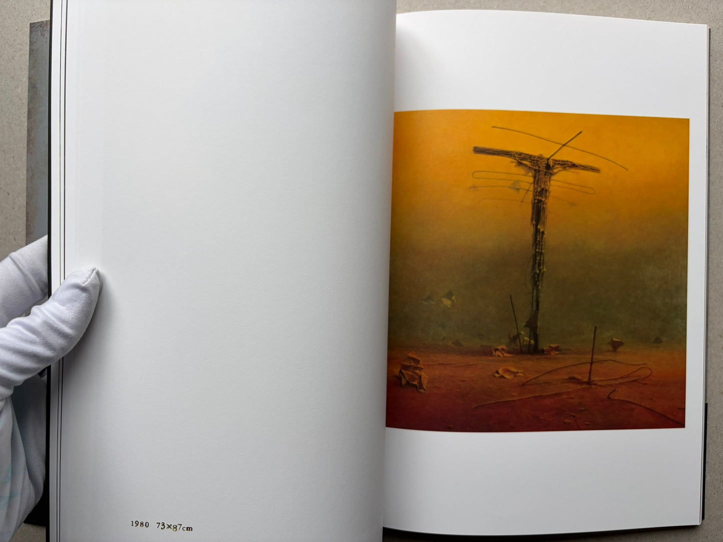 Open spread from Beksinski - The Collected Works I ver. 1.2 with a single orange painting of a tall, narrow form.