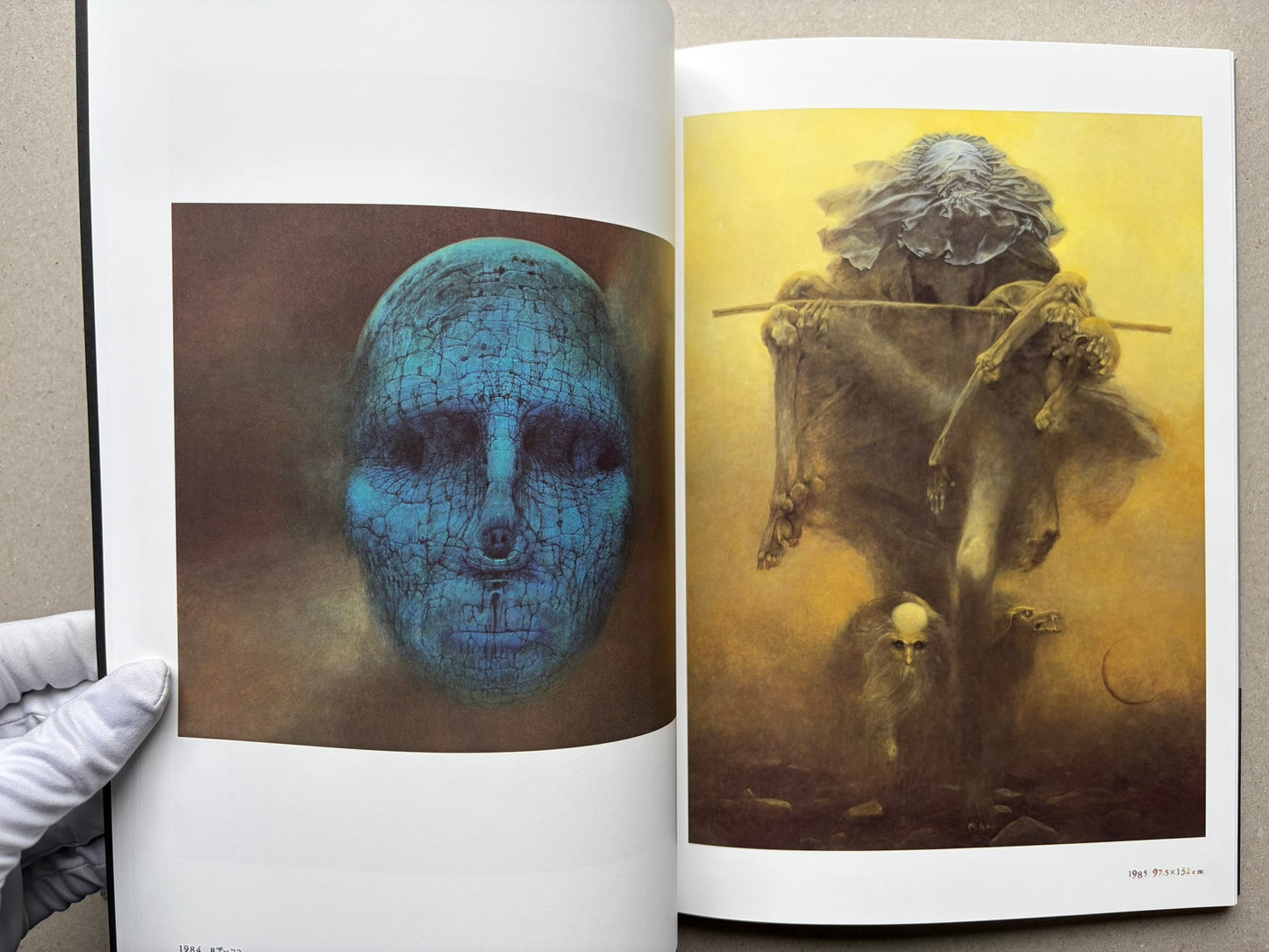 Beksiński: The Collected Works II ver. 1.2 open to a spread with a blue face and a figure holding a staff.