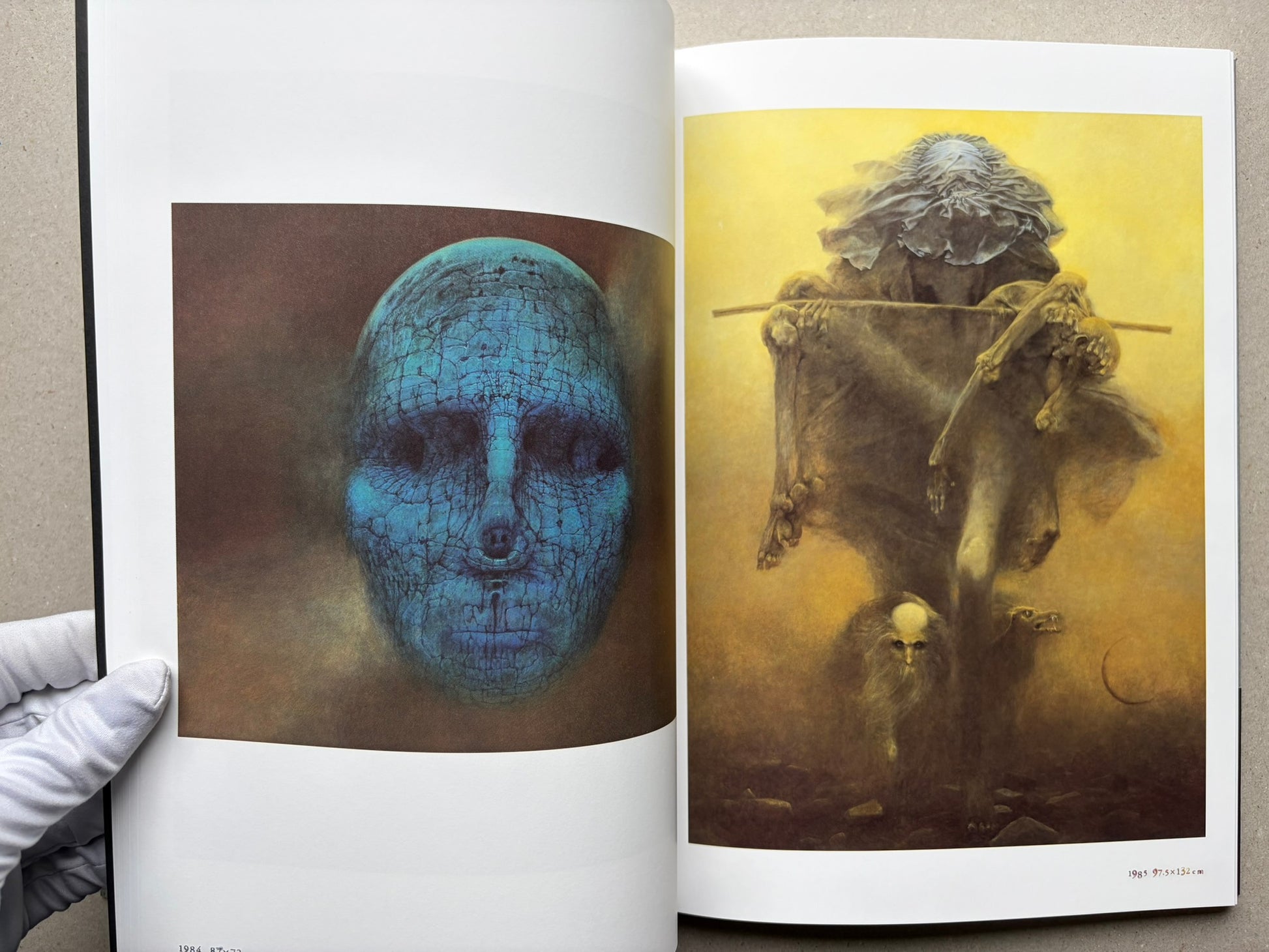 Beksiński: The Collected Works II ver. 1.2 open to a spread with a blue face and a figure holding a staff.