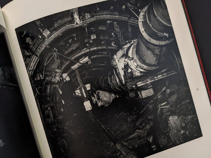 Photograph of a dark underground mining tunnel with heavy machinery, from Berg Werk by Sincei Yamamoto