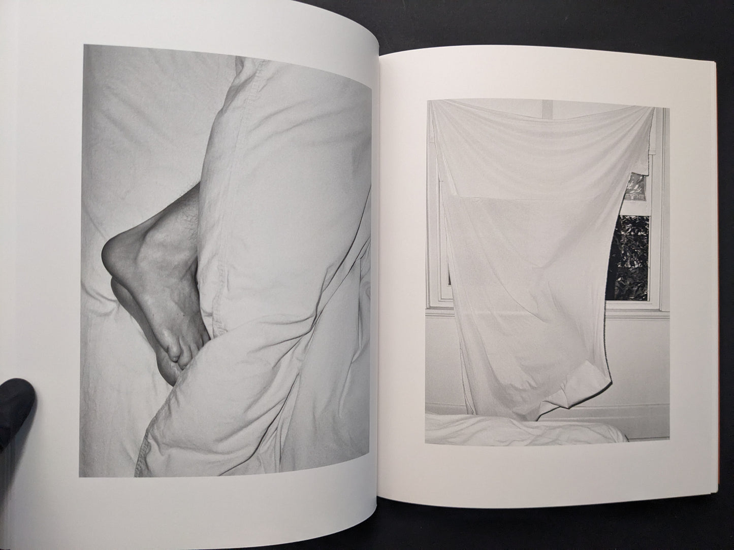 Interior spread from between the skin and sea by Katrin Koenning showing a close-up of bare feet and a sheet hanging in front of a window.