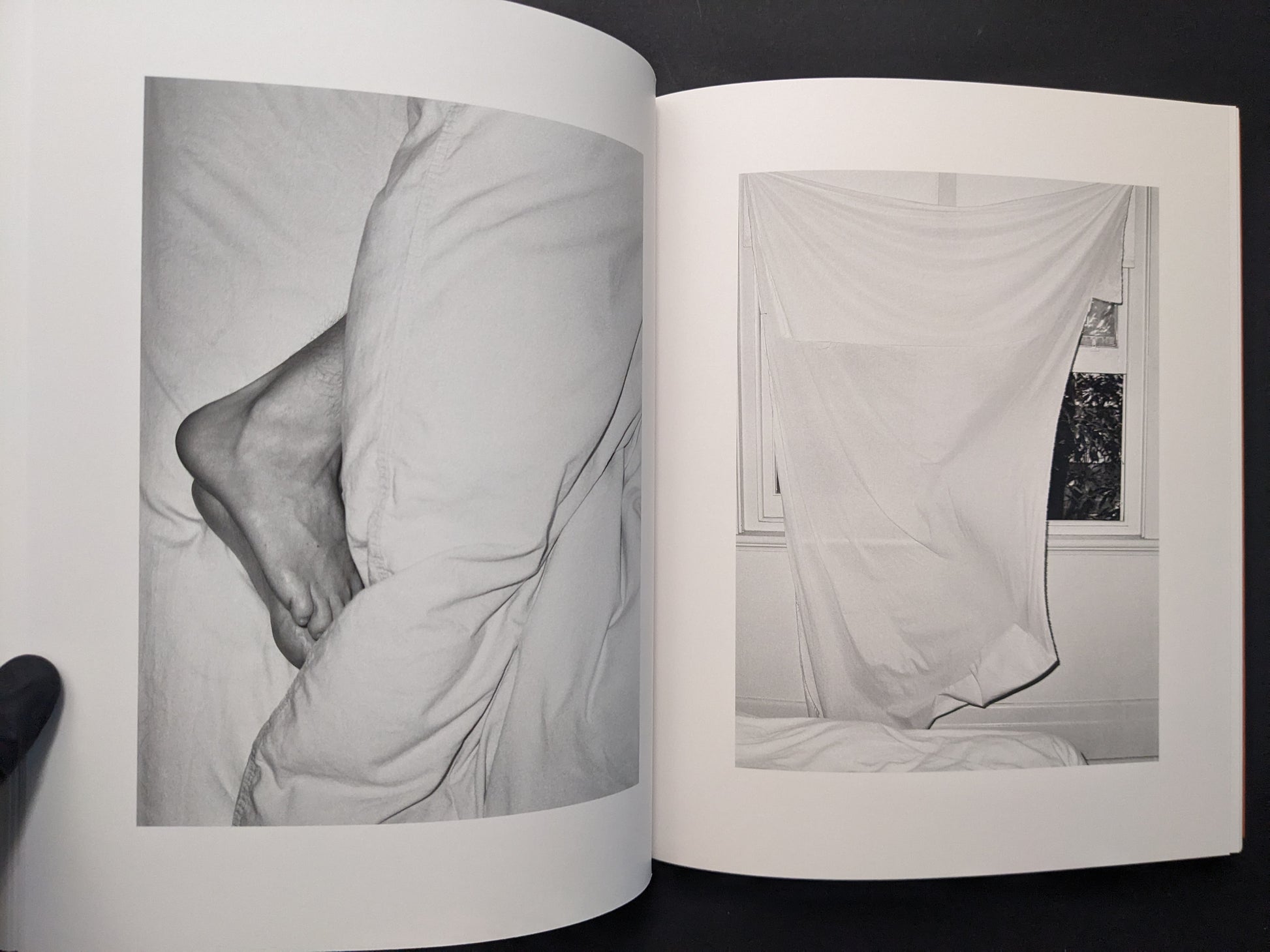 Interior spread from between the skin and sea by Katrin Koenning showing a close-up of bare feet and a sheet hanging in front of a window.