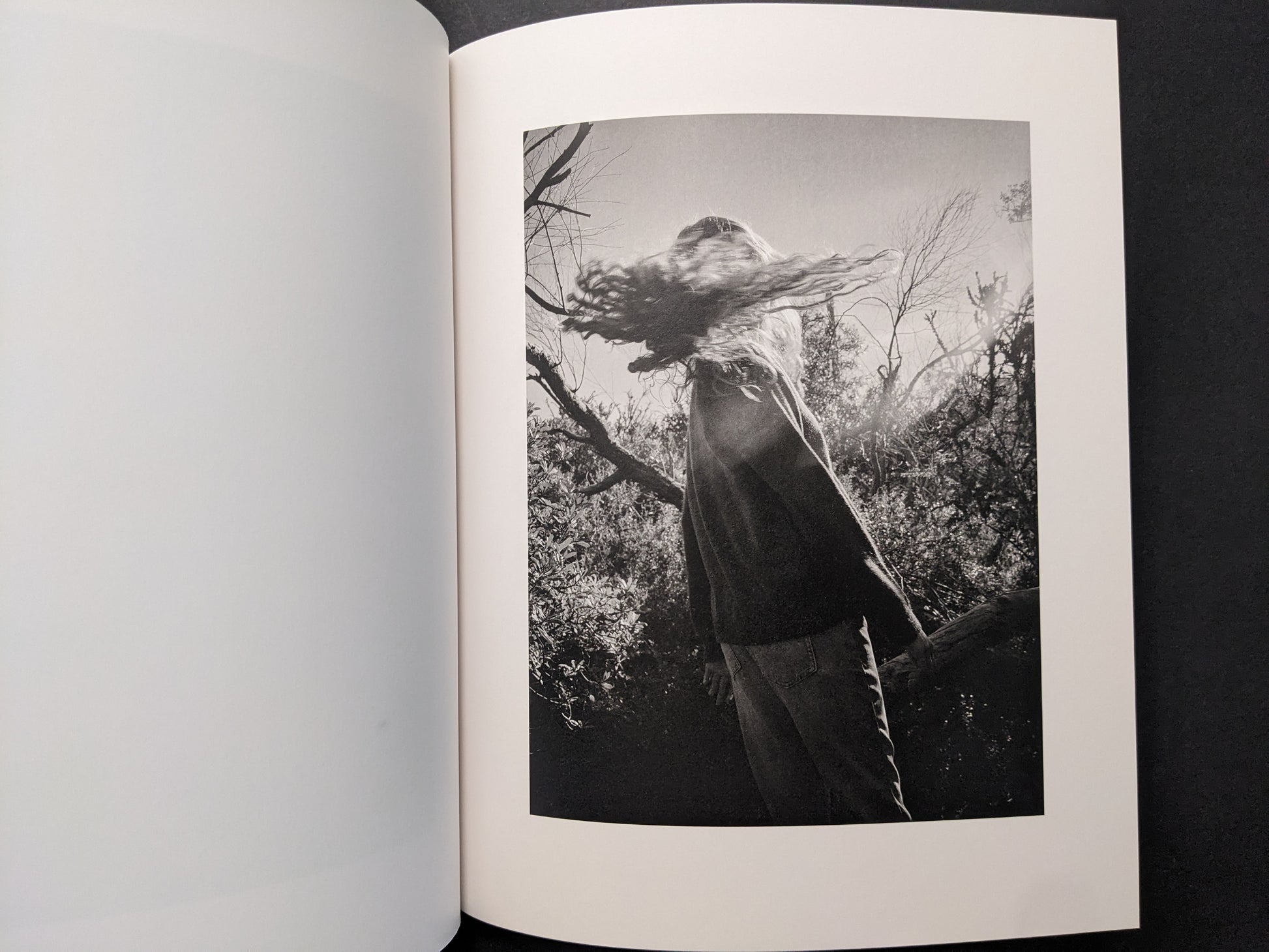 Interior photograph from “between the skin and sea” by Katrin Koenning: person outdoors with hair blown across the face.