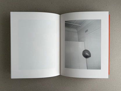 Open photobook spread from between the skin and sea by Katrin Koenning, showing a pale blank left page and a grayscale interior photograph on the right page.