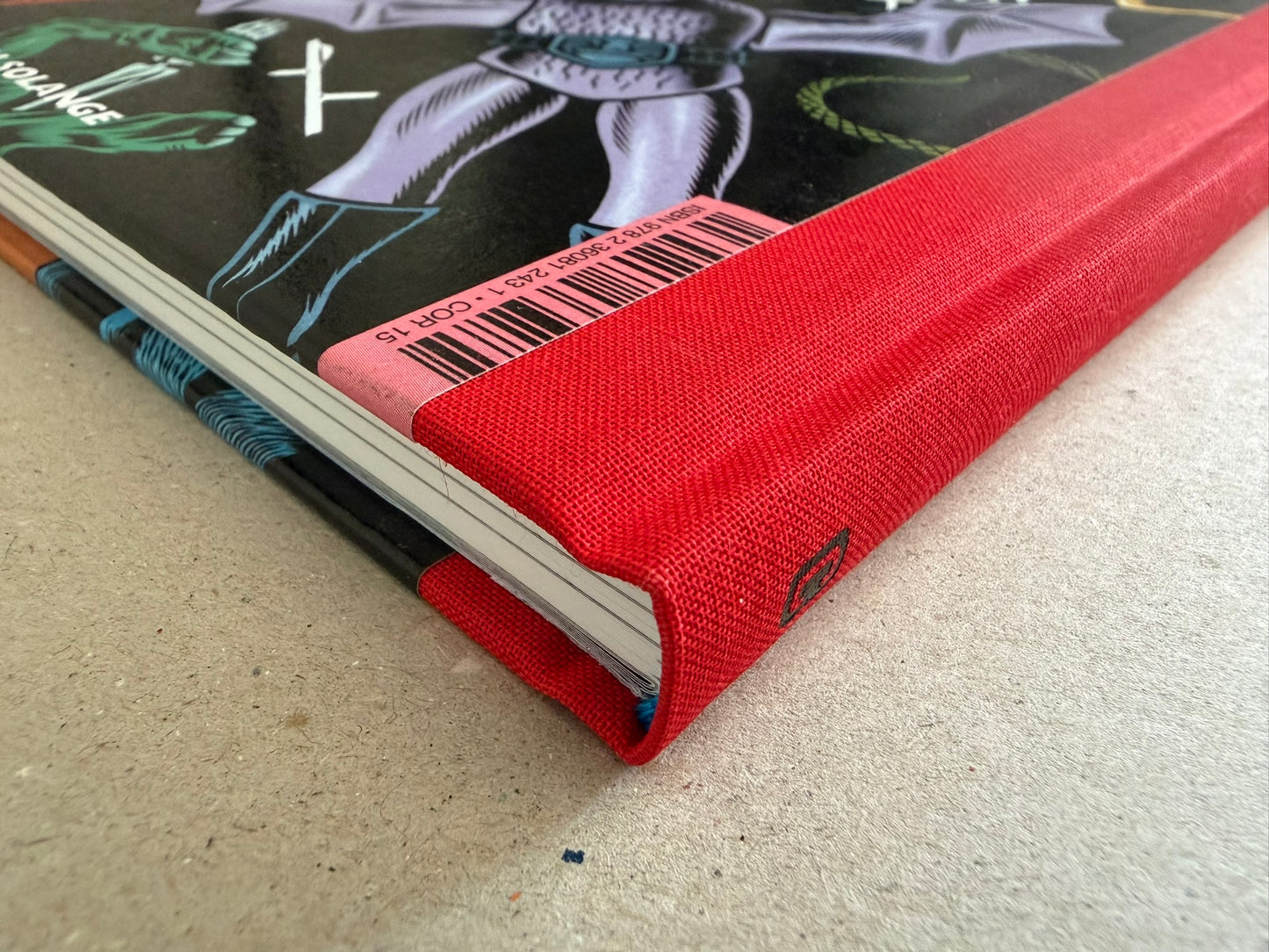 Close-up of the red cloth spine and lower cover edge of Big Baby by Charles Burns.