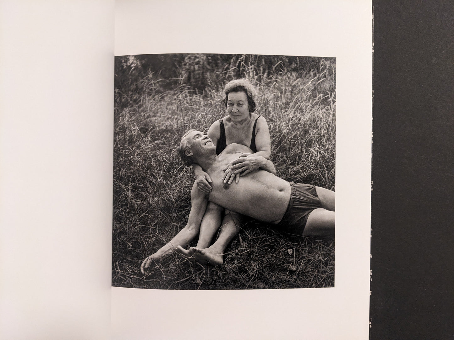 Interior photo from Cheryomushki: black-and-white portrait of an older couple resting in grass, posed affectionately.