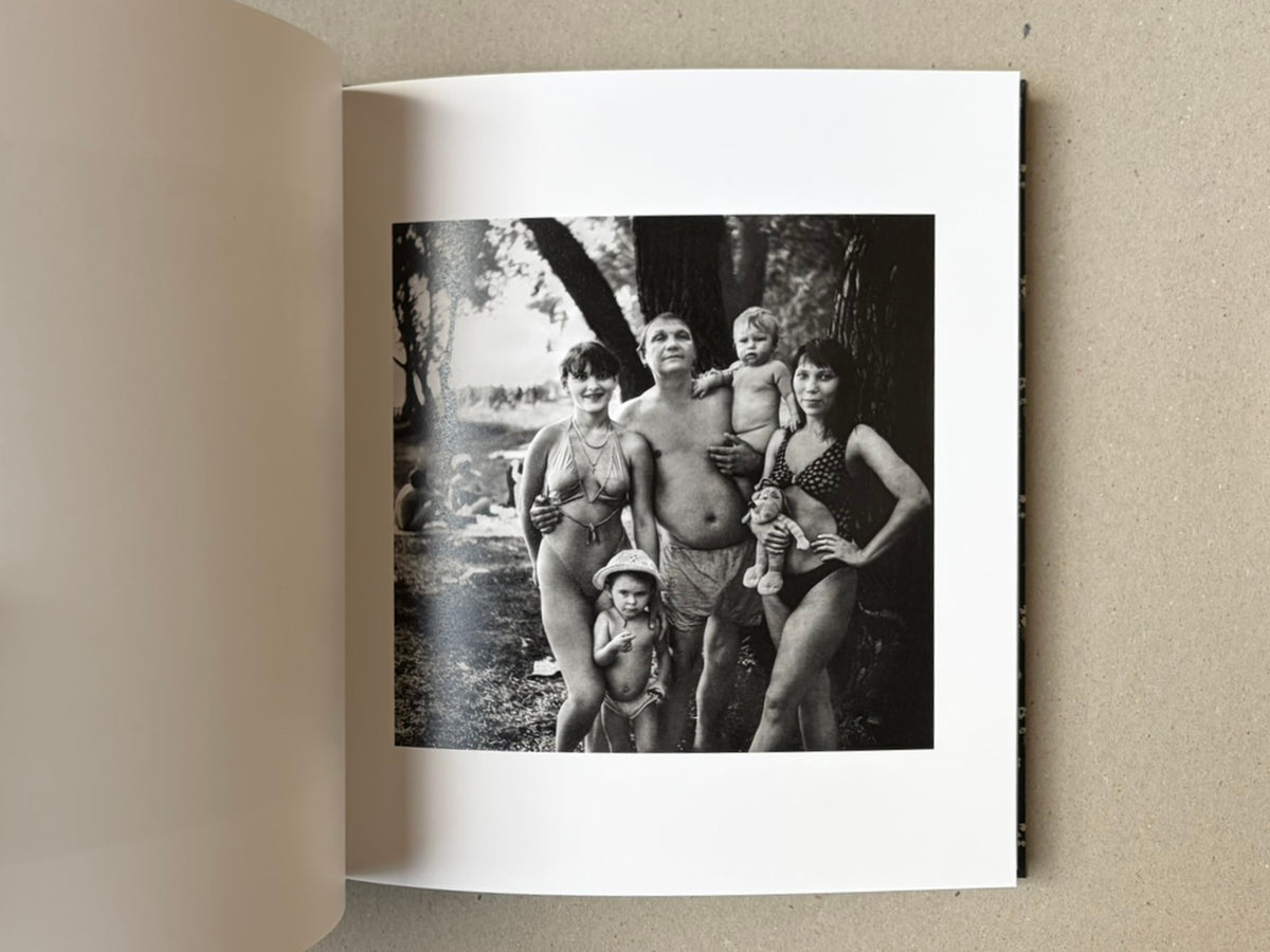 Open book page from Cheryomushki — Nikolay Bakharev showing a black-and-white photograph of a family group standing outdoors by a tree.