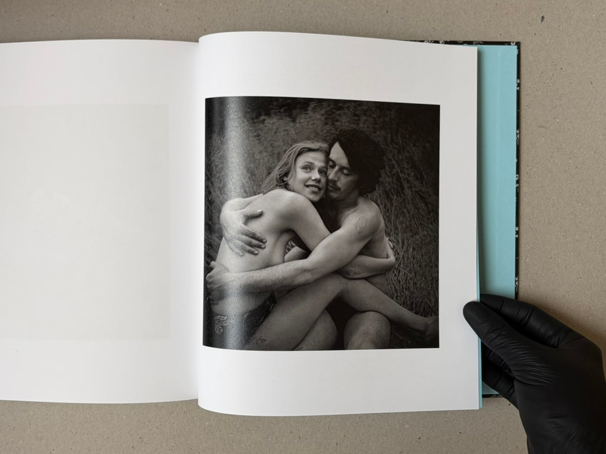 Open book spread showing a black-and-white photograph from Cheryomushki by Nikolay Bakharev, with a nude couple embracing on the right-hand page.