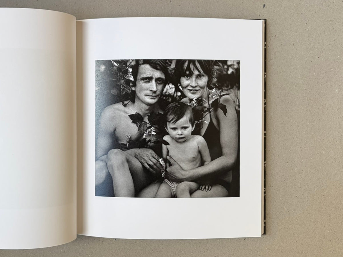 Open book spread showing a black-and-white photograph from Cheryomushki by Nikolay Bakharev: a seated man, woman, and child posed closely together.