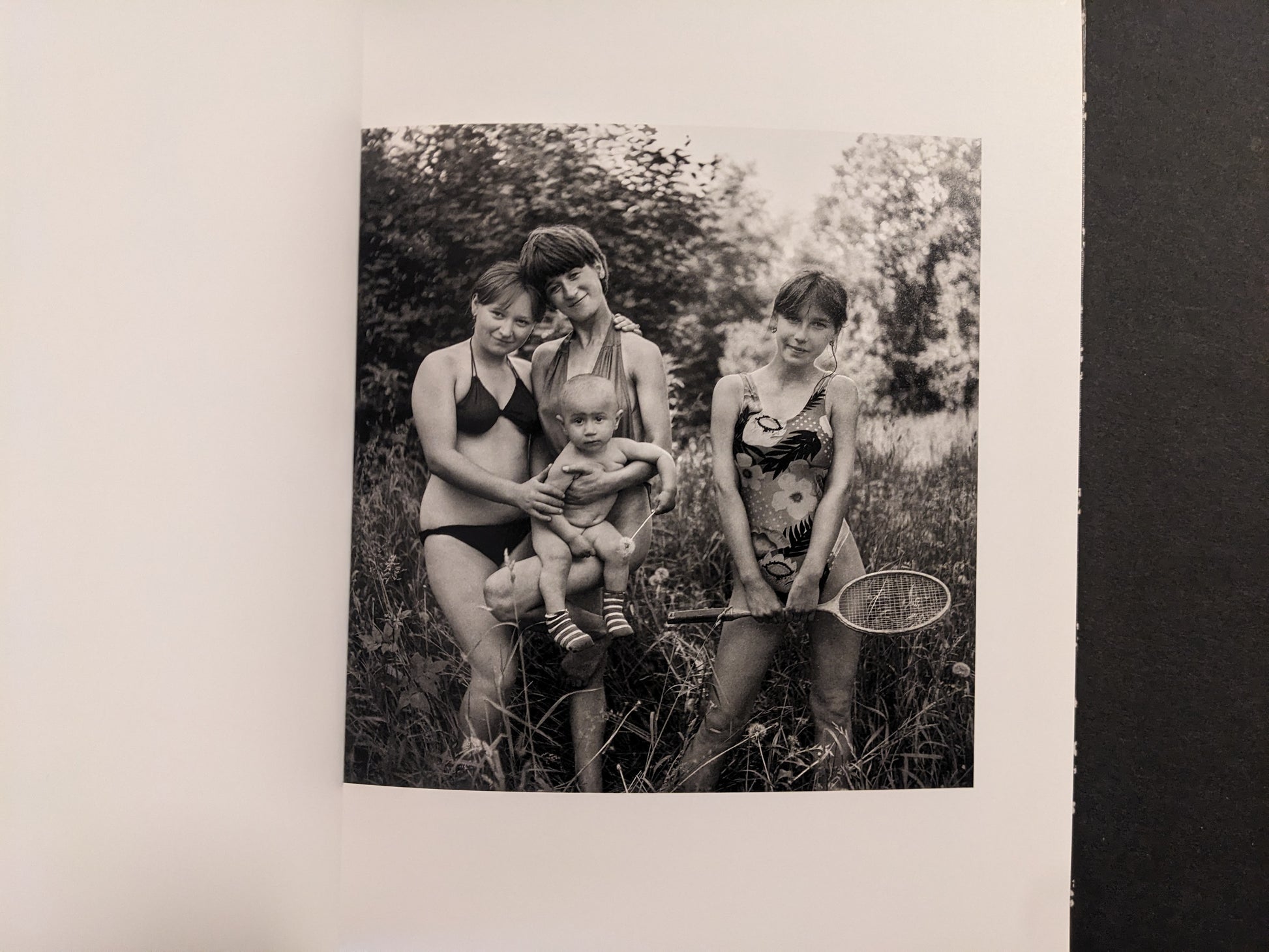 Cheryomushki by Nikolay Bakharev interior photo: black-and-white portrait of three girls with a toddler outdoors, one holding a badminton racket.