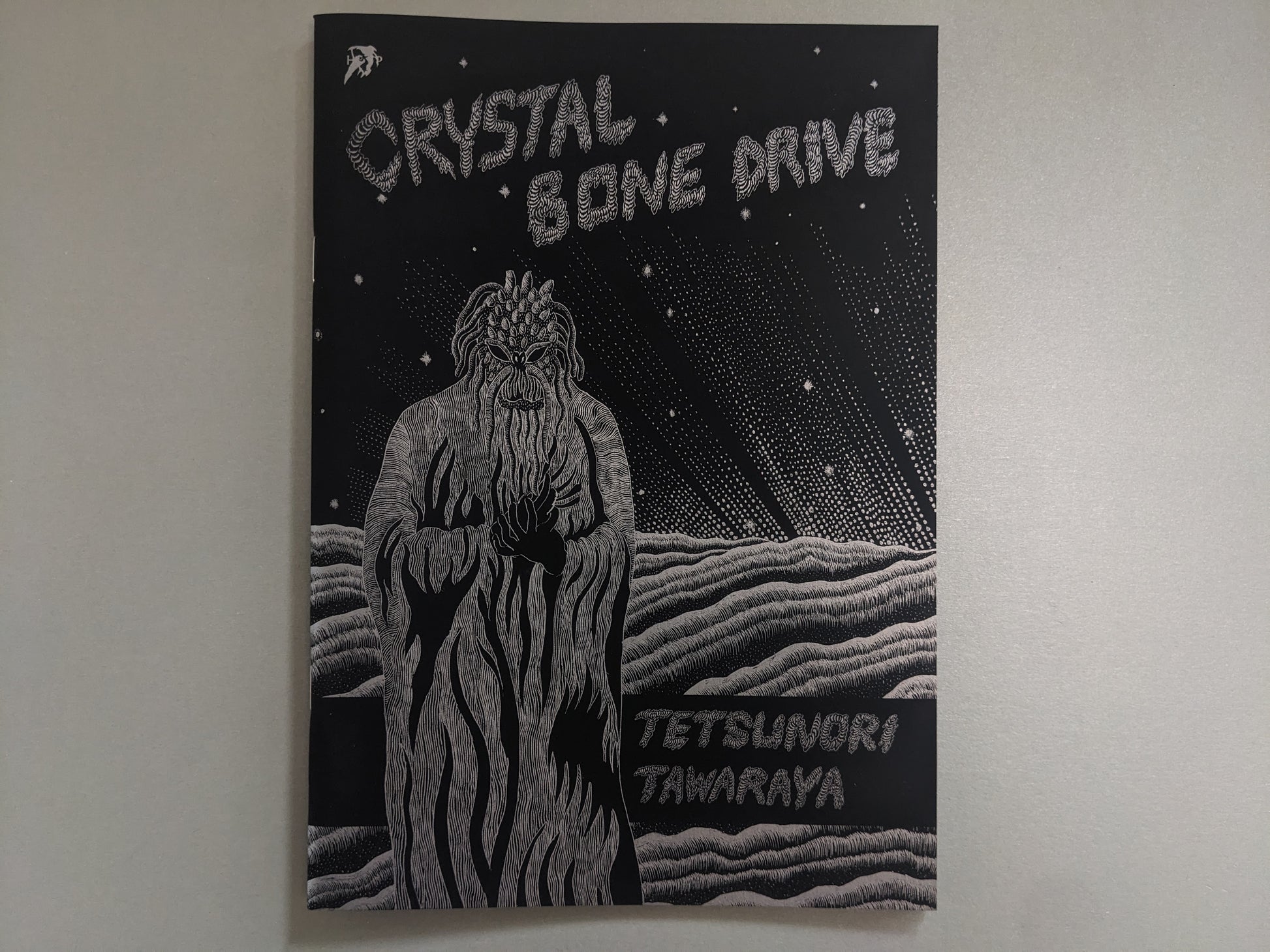 Front cover of Crystal Bone Drive by Tetsunori Tawaraya, with a silver-ink figure under cosmic rays