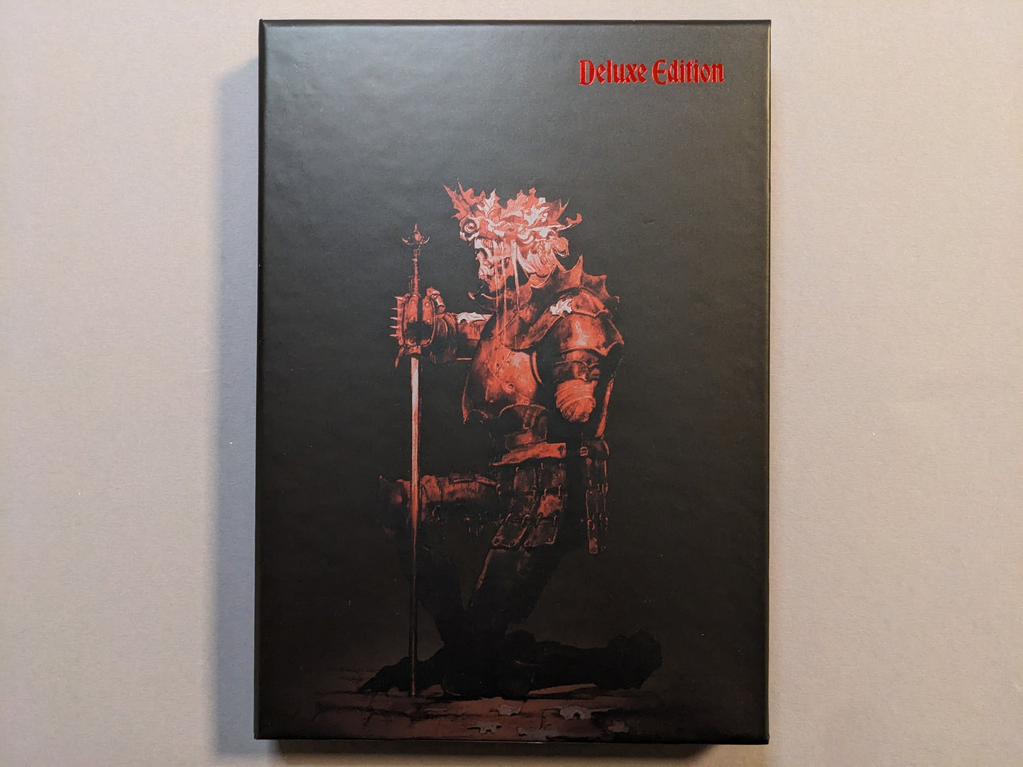 Collector slipcase for Cursed Swords with red armored-knight artwork and “Deluxe Edition” marking; hot-stamped metallic detail.