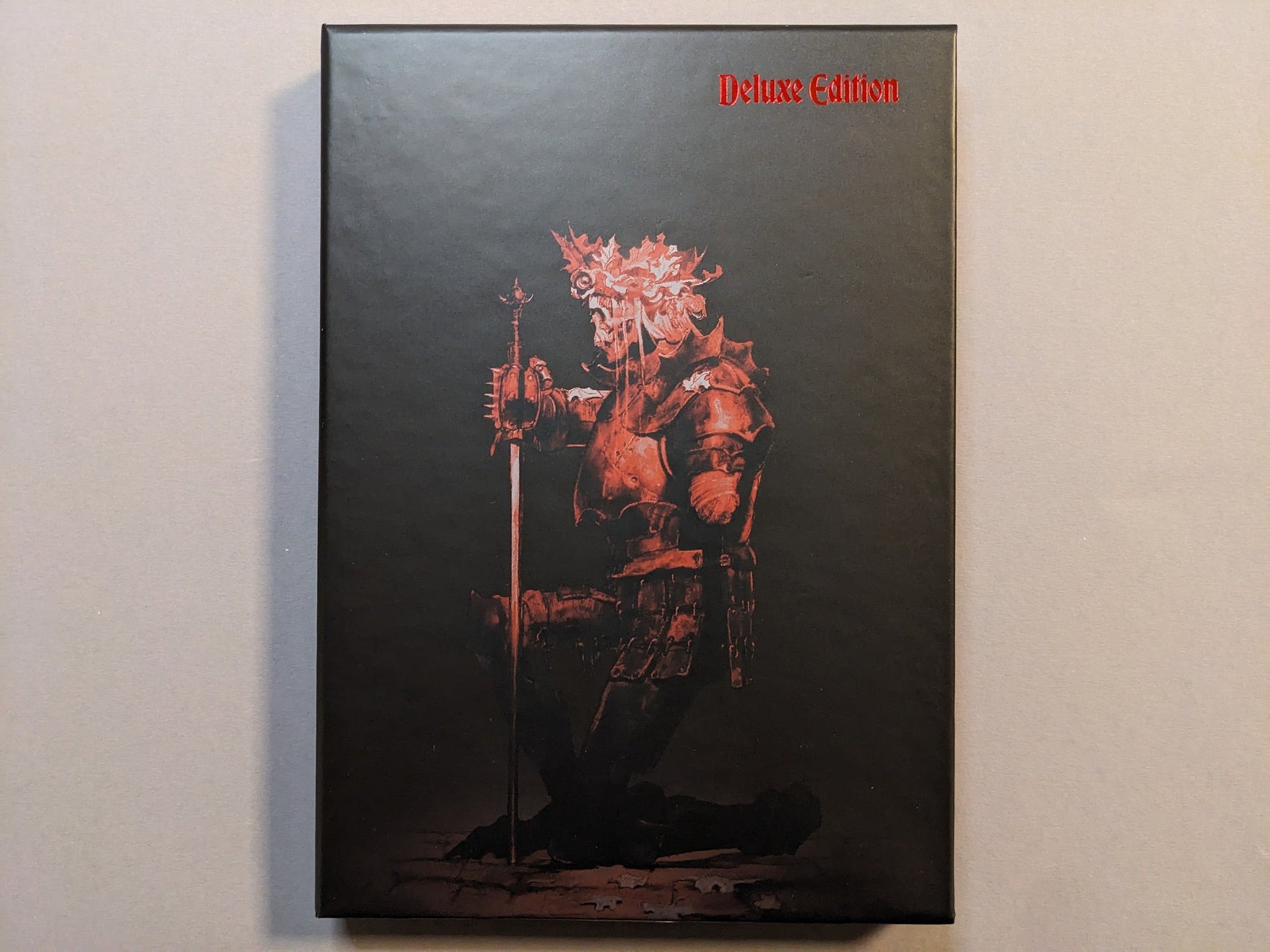 Collector slipcase for Cursed Swords with red armored-knight artwork and “Deluxe Edition” marking; hot-stamped metallic detail.