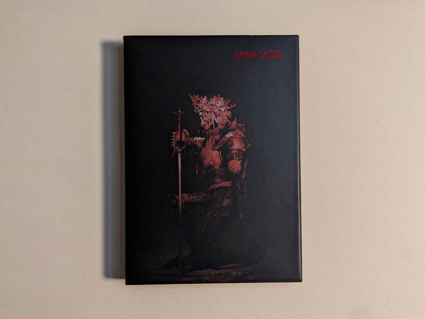 Collector slipcase for Cursed Swords with red armored-knight artwork and Deluxe Edition marking; hot-stamped metallic detail.