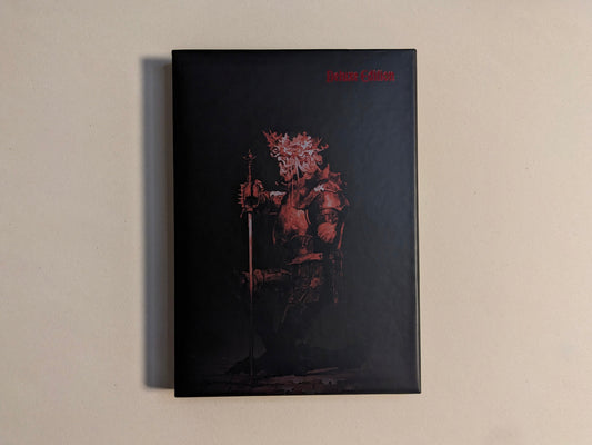 Collector slipcase for Cursed Swords with red armored-knight artwork and Deluxe Edition marking; hot-stamped metallic detail.