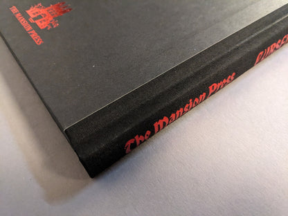 Close-up of the Cursed Swords hardcover cloth spine with red foiled “The Mansion Press” imprint.