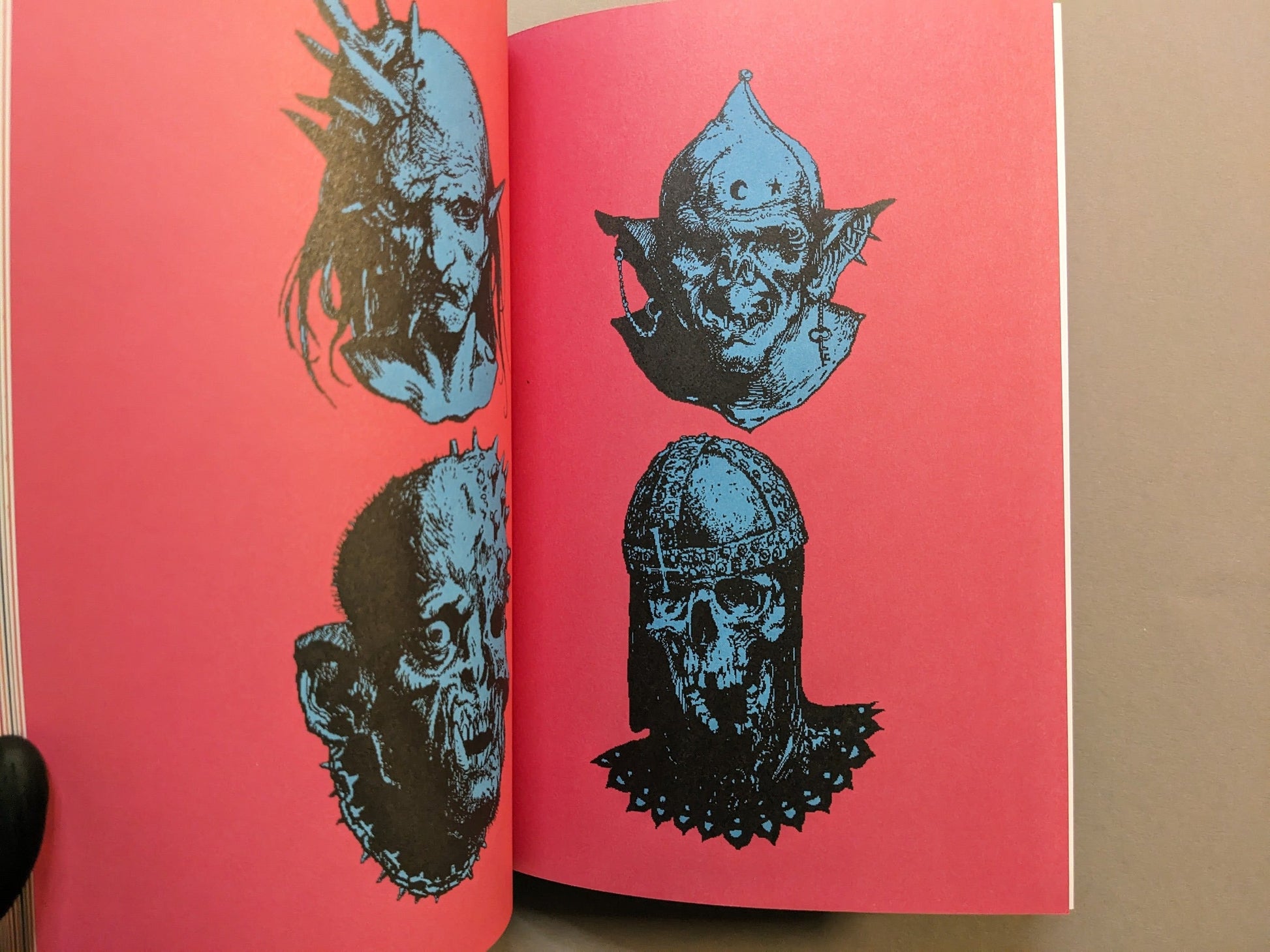 Interior endpaper with pink ground and blue prints of grotesque heads in a bold graphic style.