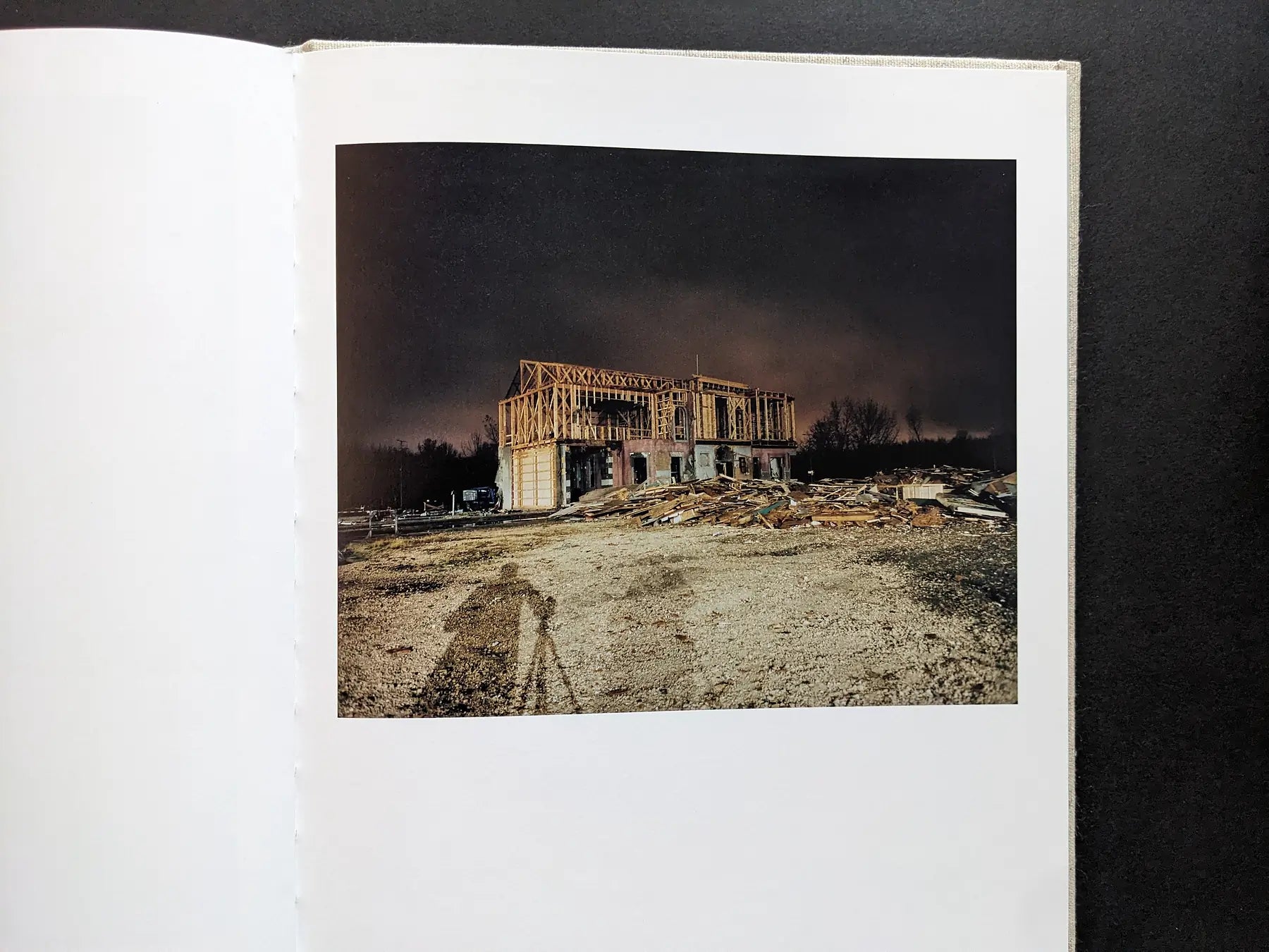 Color night view of a house façade under construction on the set; the photographer’s tripod shadow is visible.