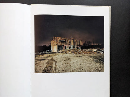 Color night view of a house façade under construction on the set; the photographer’s tripod shadow is visible.