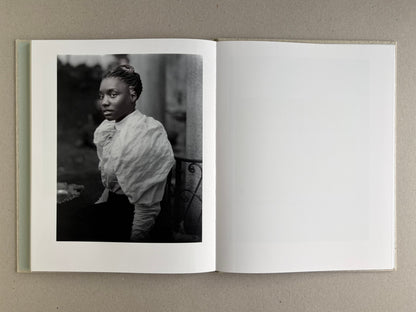 Black-and-white portrait of a woman on the left page of Dear God, the Parthenon is still broken, with a blank right page.