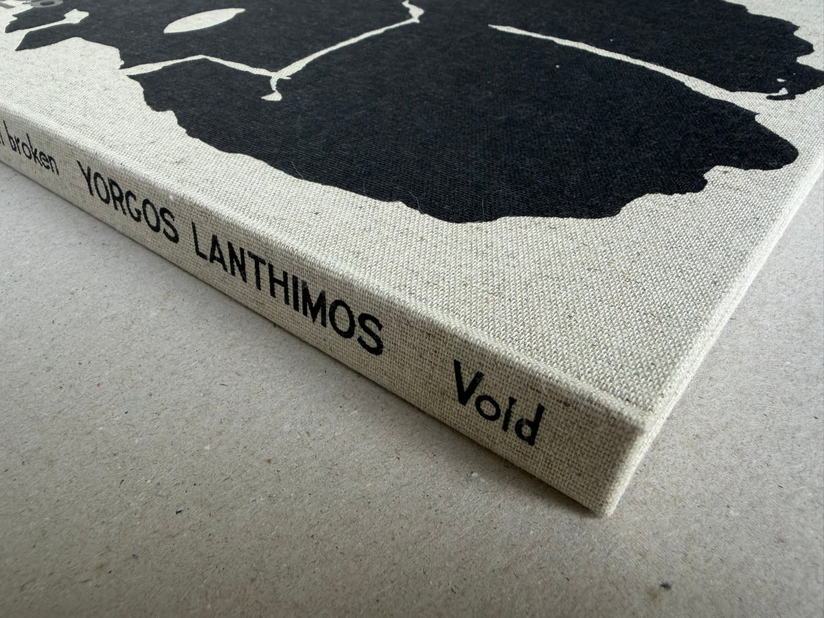 Close view of the cloth spine of Dear God, the Parthenon is still broken by Yorgos Lanthimos, with the title and Void printed in black.