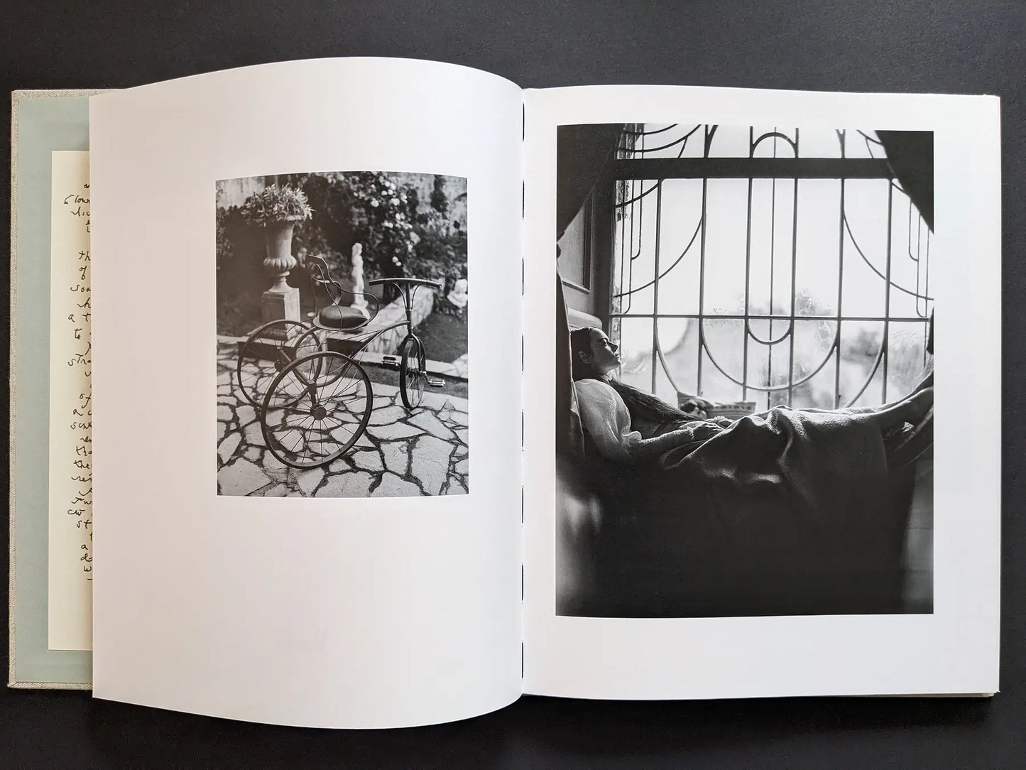 Black-and-white photographs of a tricycle and a resting figure by a window.