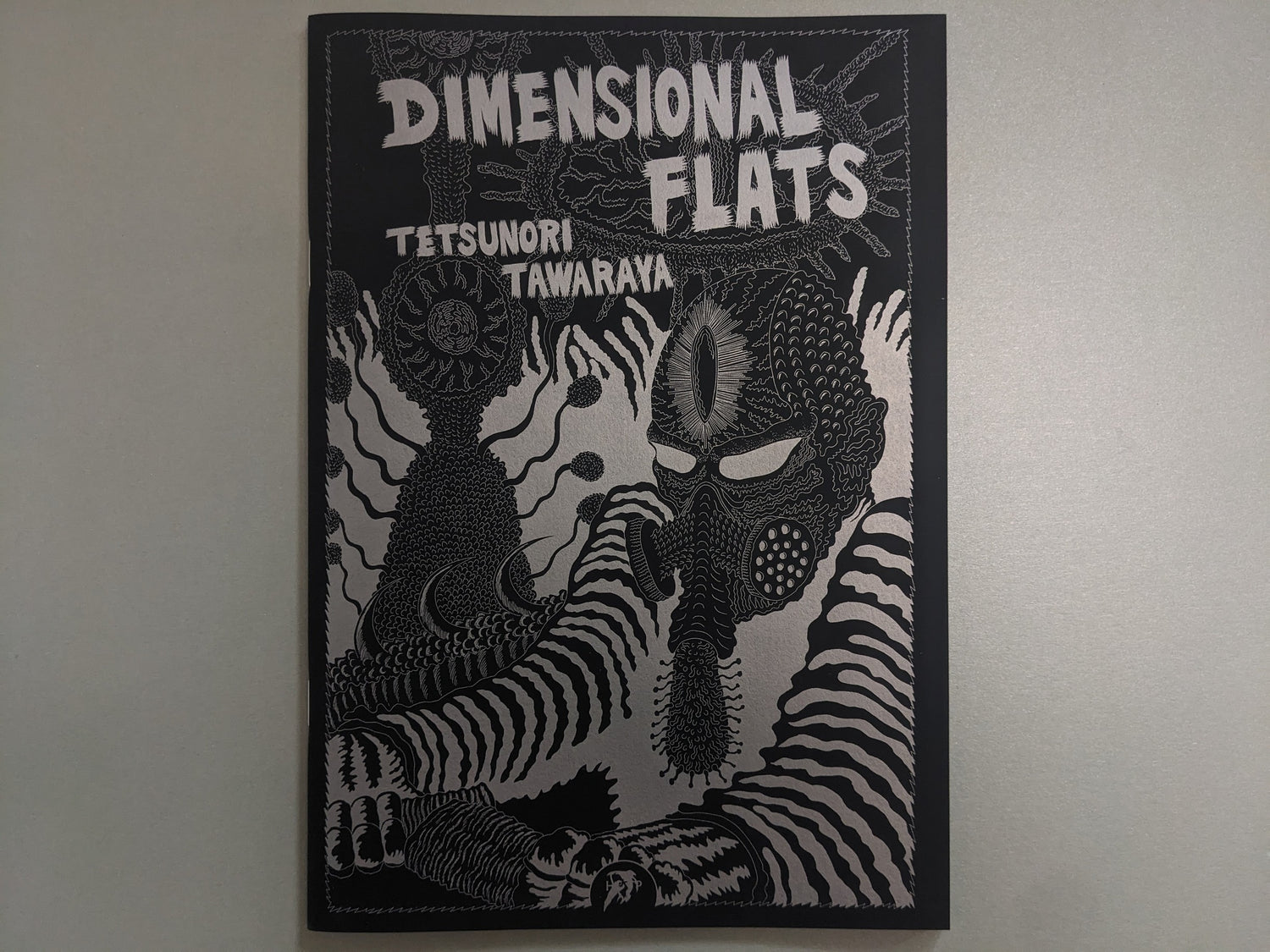 Front cover of Dimensional Flats by Tetsunori Tawaraya, showing a masked mutant figure and cosmic forms in silver ink.