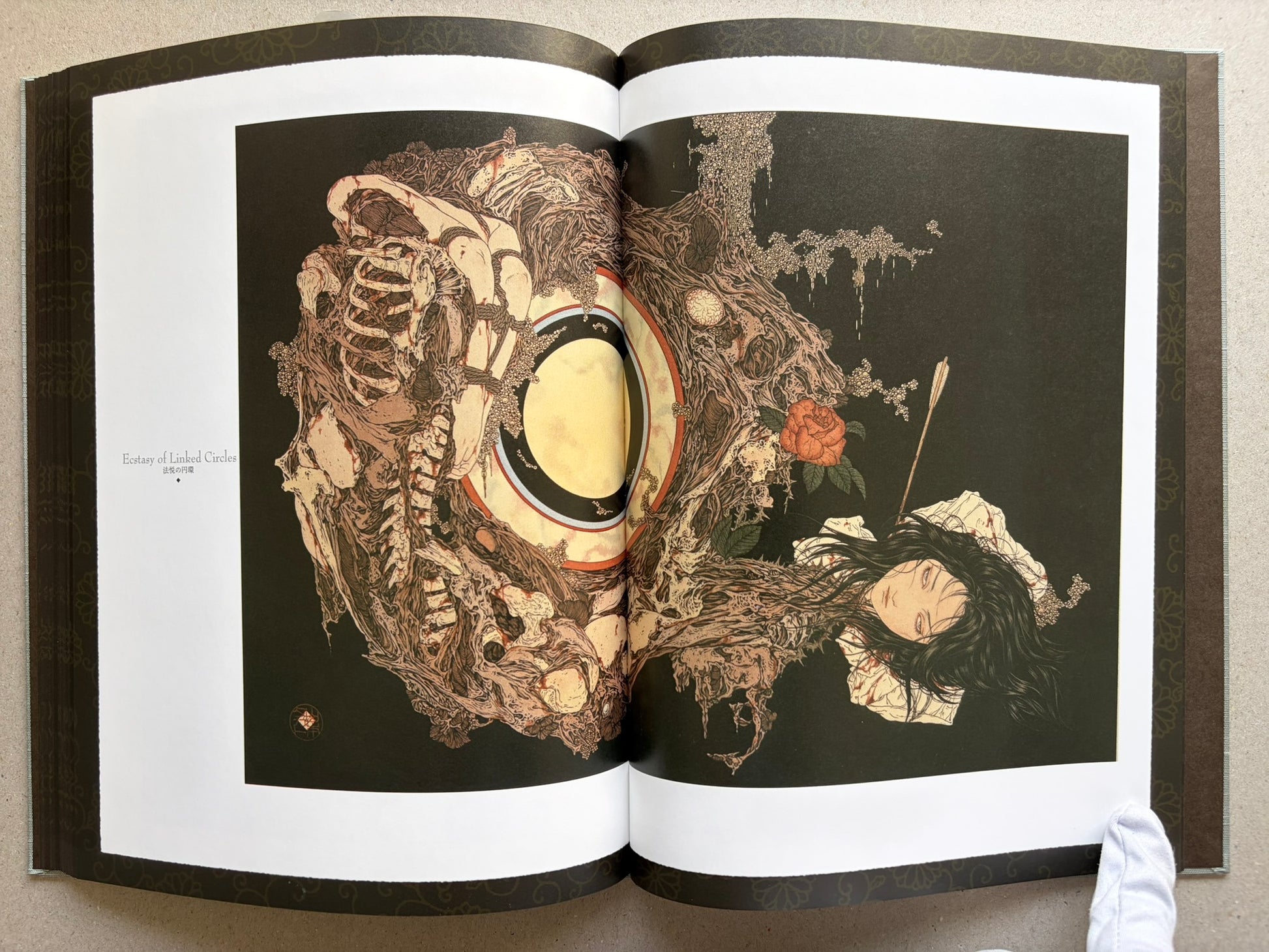 Divertimento for a Martyr – Takato Yamamoto New Black Edition, open spread with with a large skull-like form, a yellow circular element, dark background, and a reclining figure with a rose.