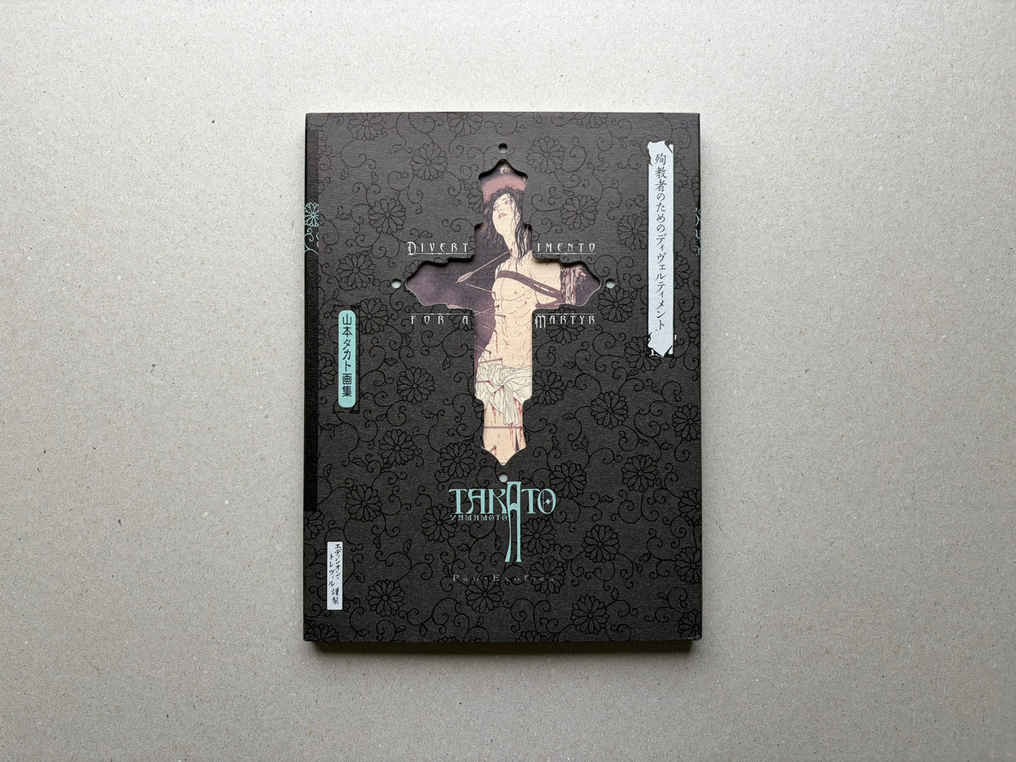 Divertimento for a Martyr – Takato Yamamoto New Black Edition, front cover with black patterned sleeve and cross-shaped cutout