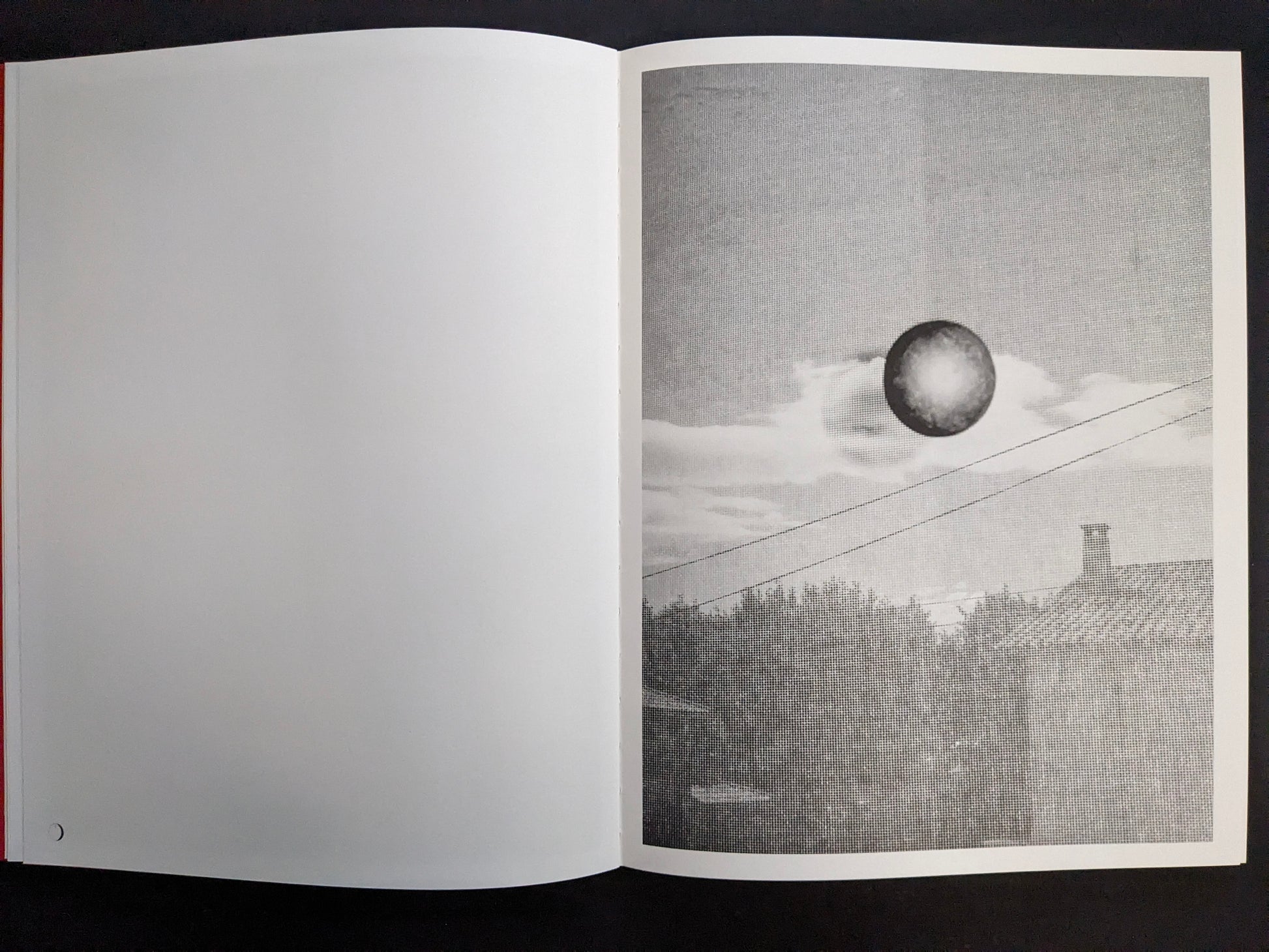 Interior page with a grainy monochrome sky scene featuring a dark circular orb above clouds and rooftops.