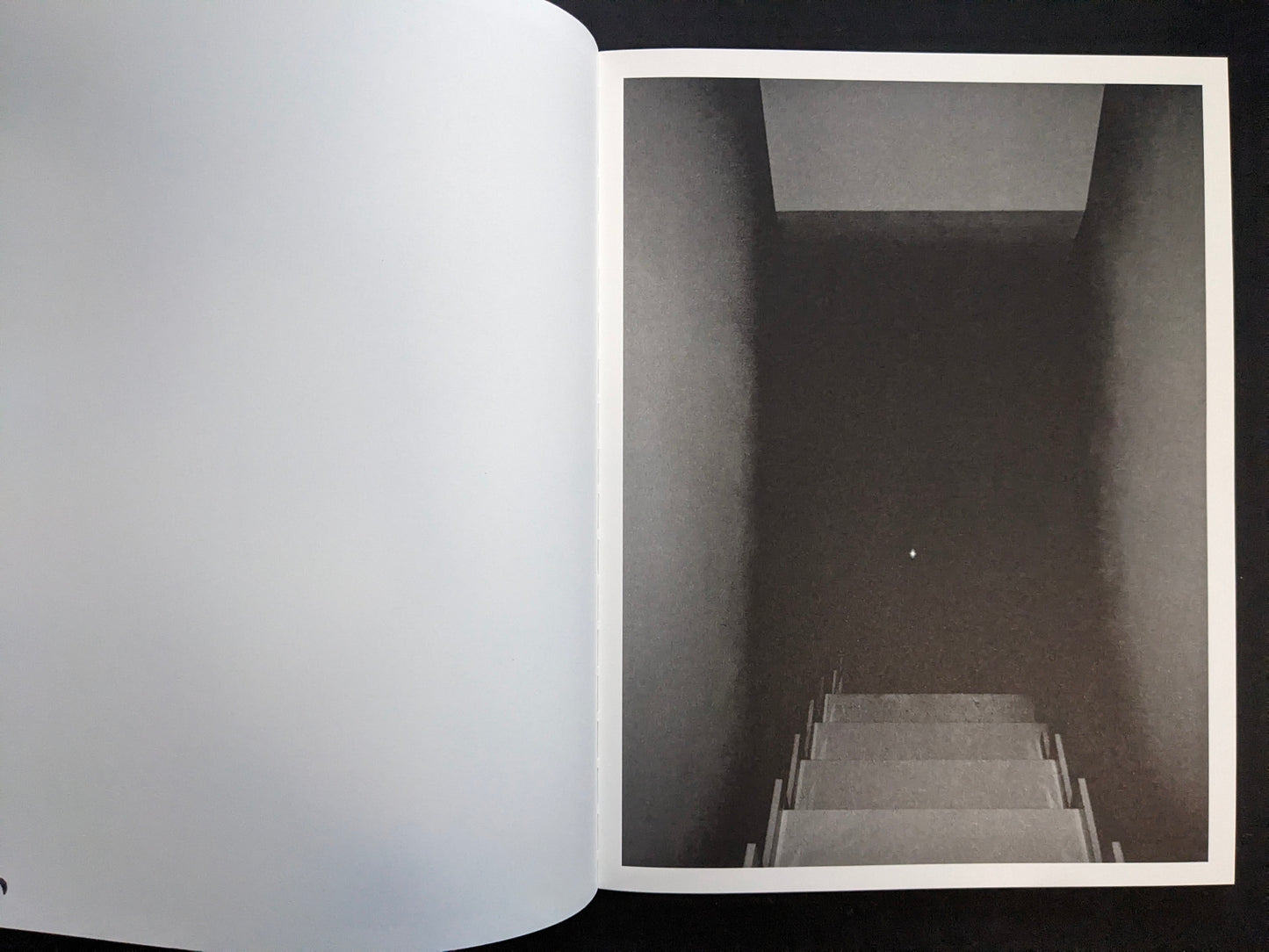 Interior page with a monochrome photograph looking down a stairwell into darkness.