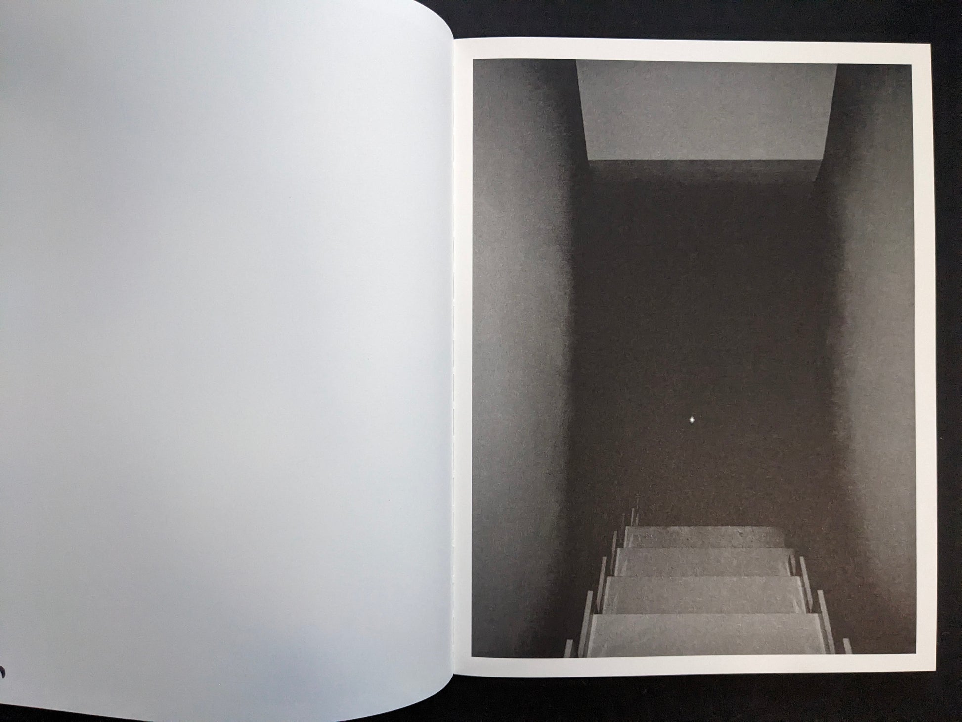 Interior page with a monochrome photograph looking down a stairwell into darkness.