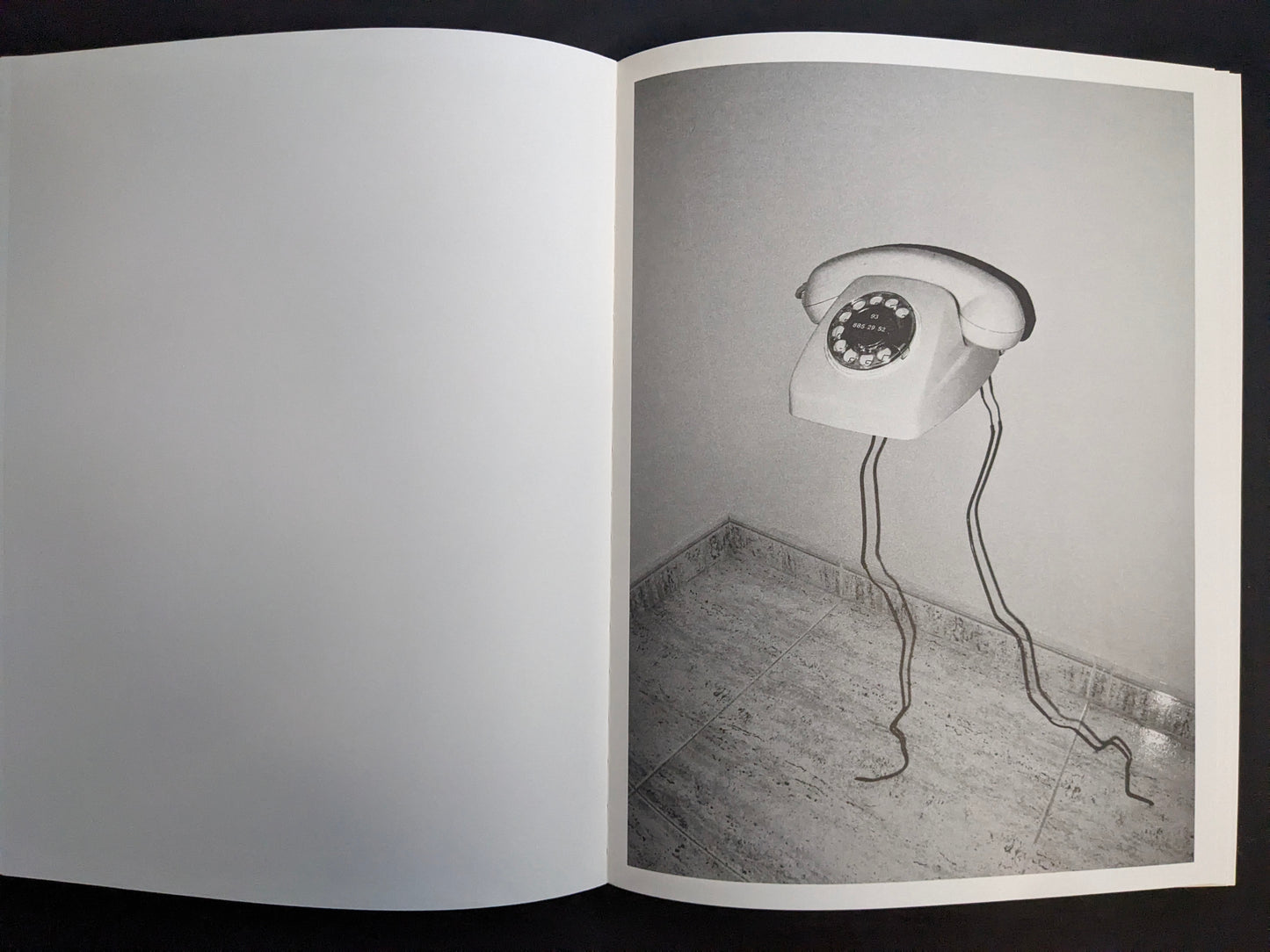 Interior page with a monochrome photograph of a rotary telephone mounted on a wall with its cord hanging down.