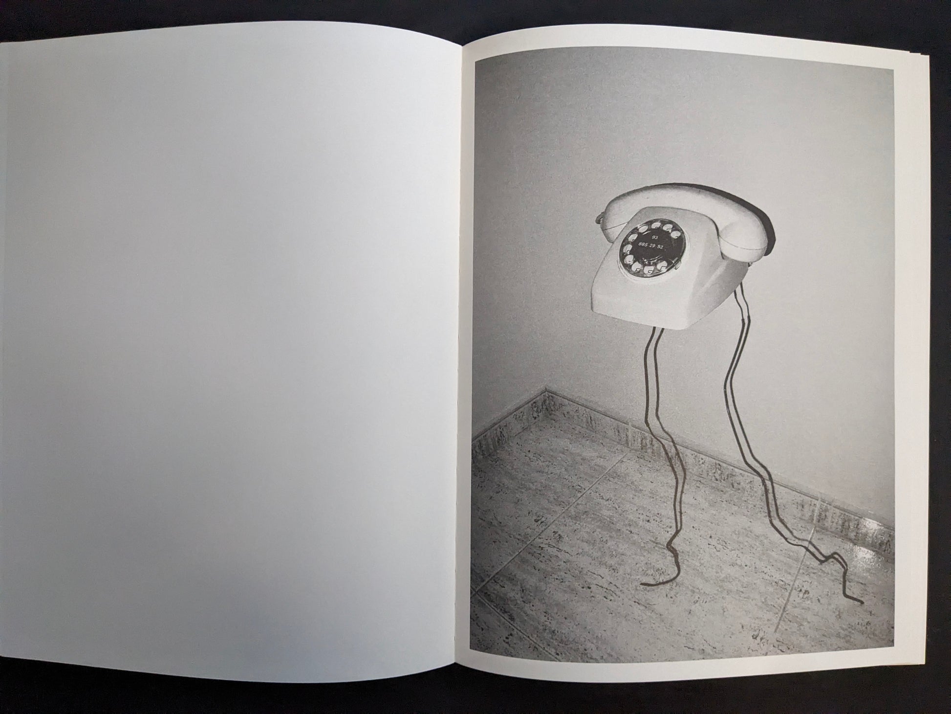 Interior page with a monochrome photograph of a rotary telephone mounted on a wall with its cord hanging down.