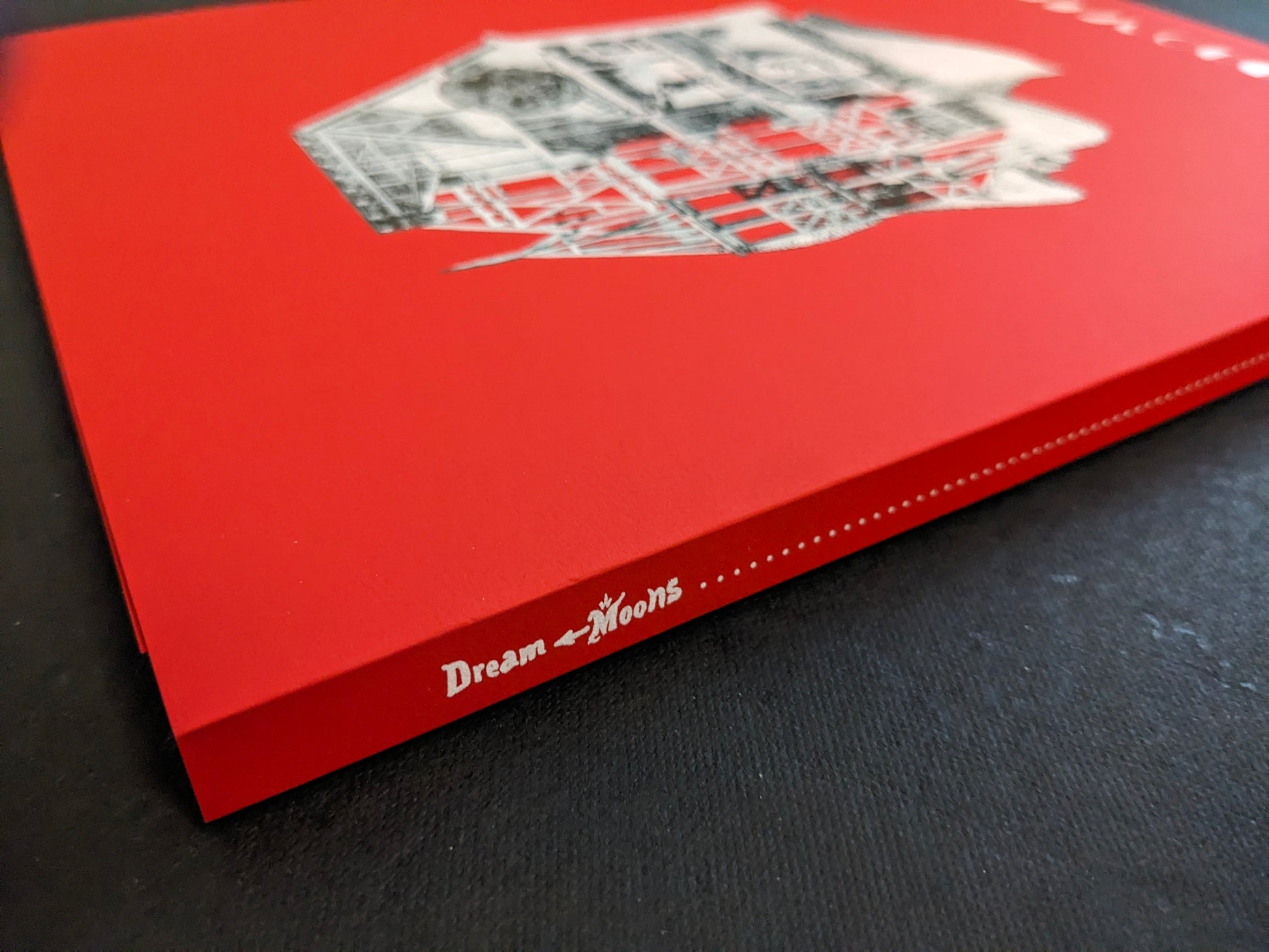 Spine detail of “Dream Moons” by Yurian Quintanas Nobel (Void) on a red cloth-bound book.